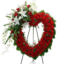 Heart-shaped red floral wreath on a stand with white flowers