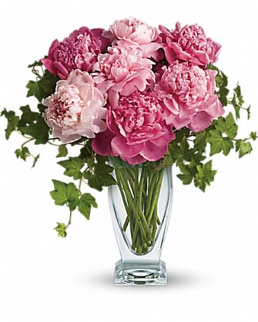 Pink peonies arranged in a clear glass vase with trailing ivy