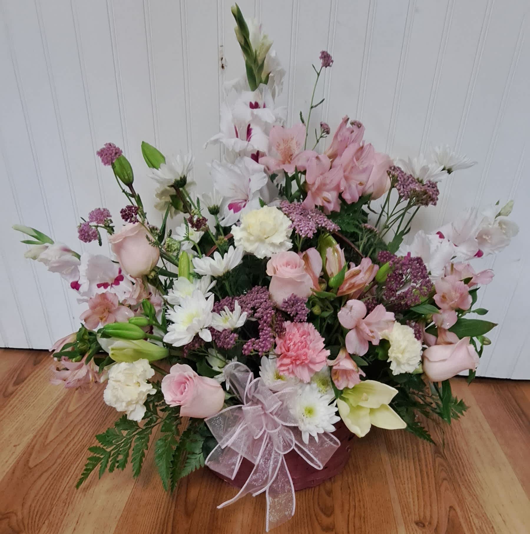 Pink and white mixed flower arrangement in a basket with a ribbon