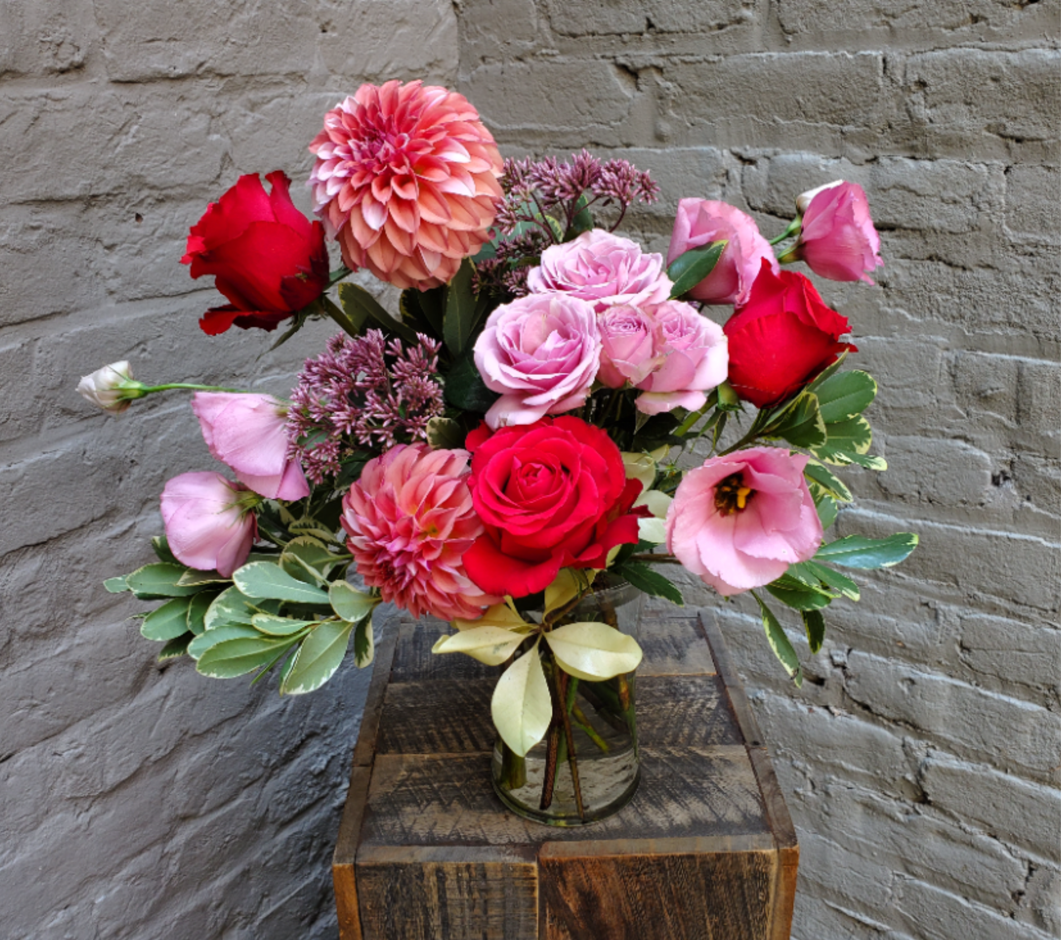 Summer Splash! - A bright and punchy parade of color!  Vivid coral roses, local raspberry dahlias, and perfectly pink lisianthus create a fun and bold display in a clear glass gathering vase.  Standard arrangement measures approximately 15" wide by 17" tall.