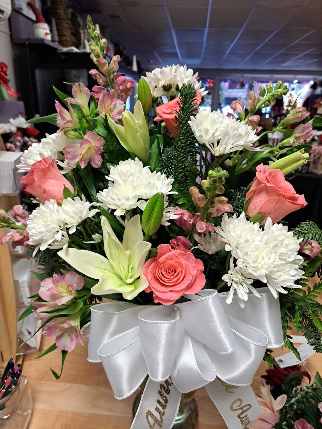 Bouquet of pink roses, white lilies, and white chrysanthemums with a white ribbon