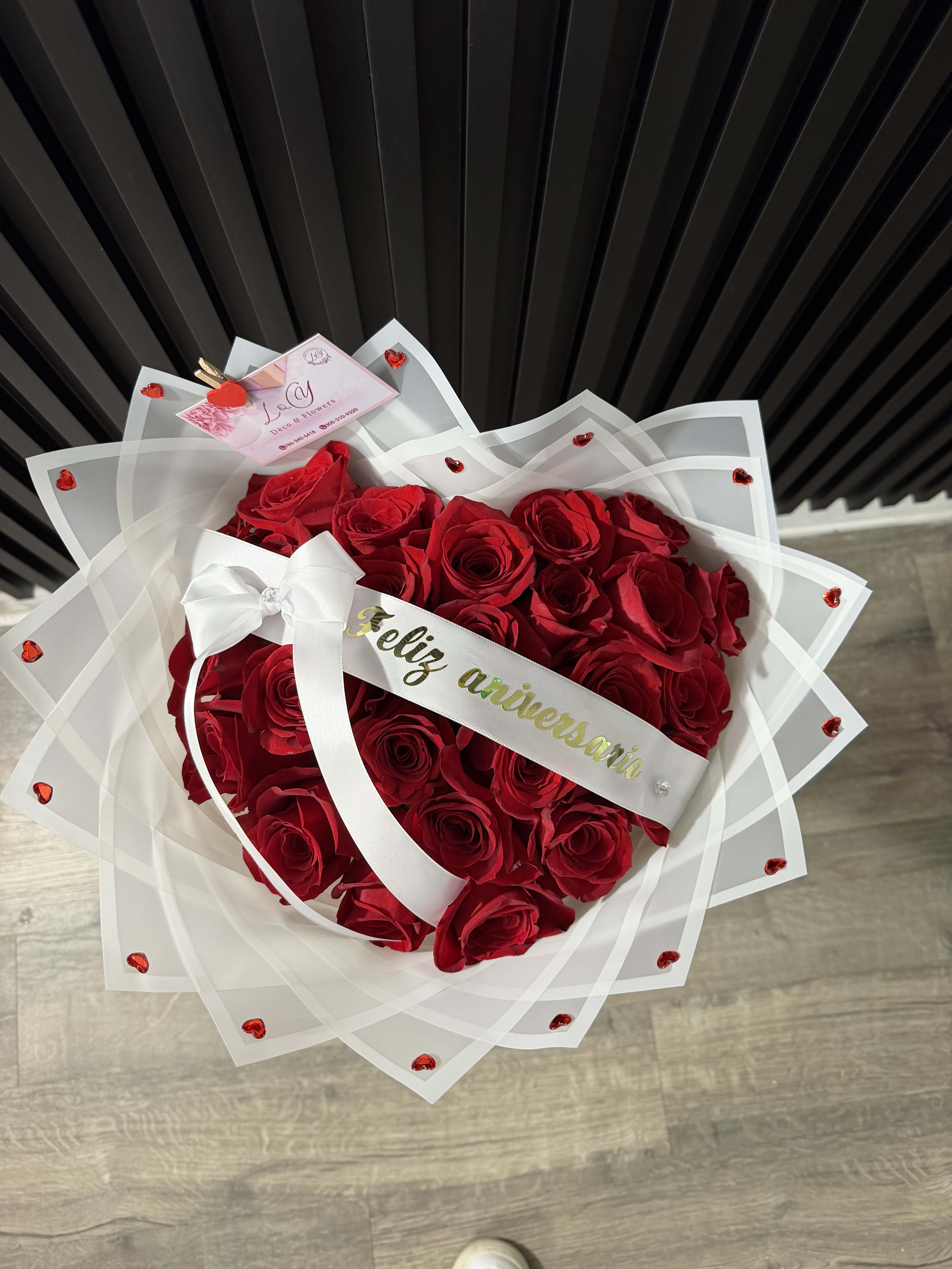 Heart-shaped bouquet of red roses wrapped in white paper with a ribbon