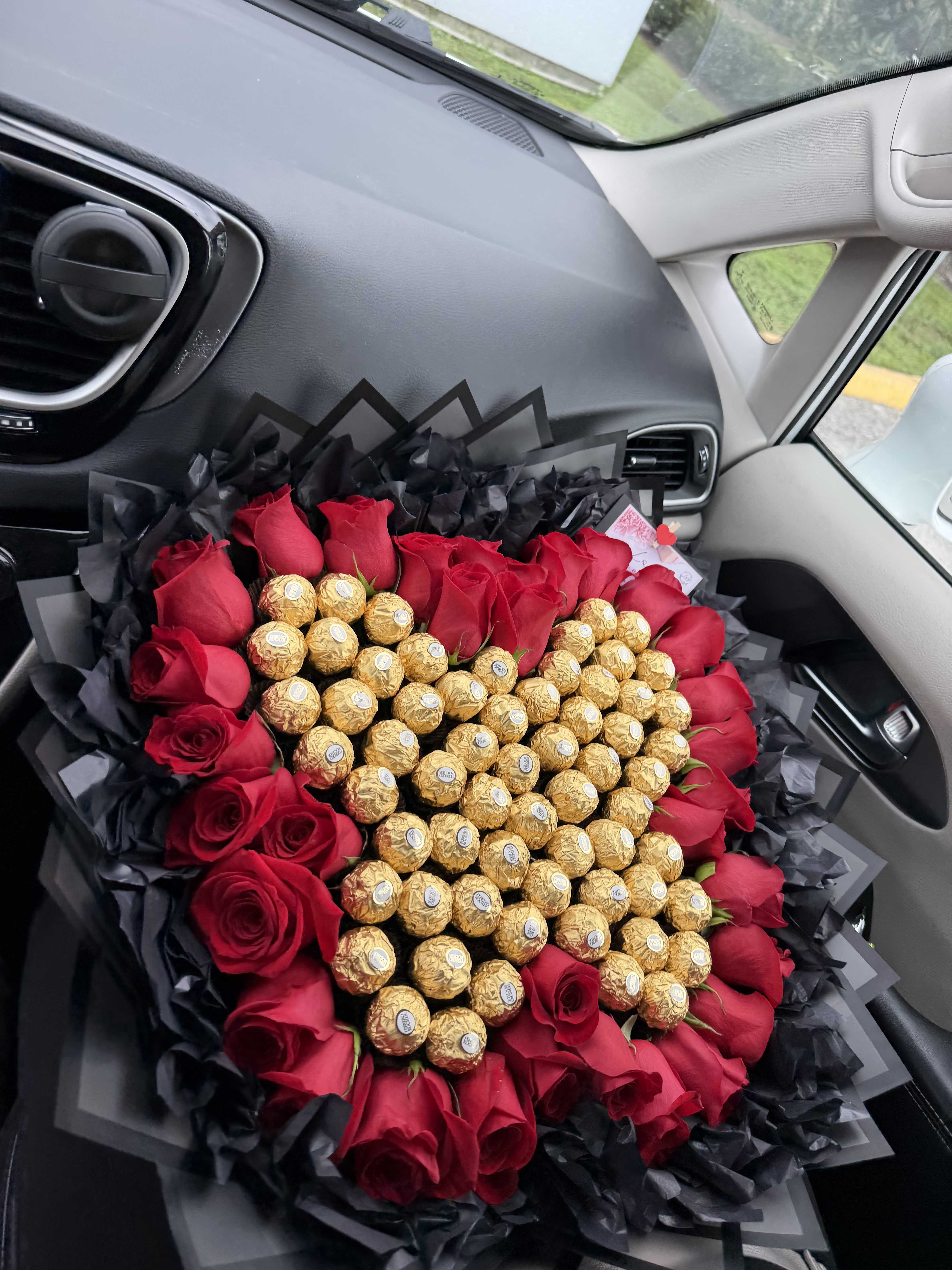 Heart-shaped bouquet of red roses and gold chocolates wrapped in black paper