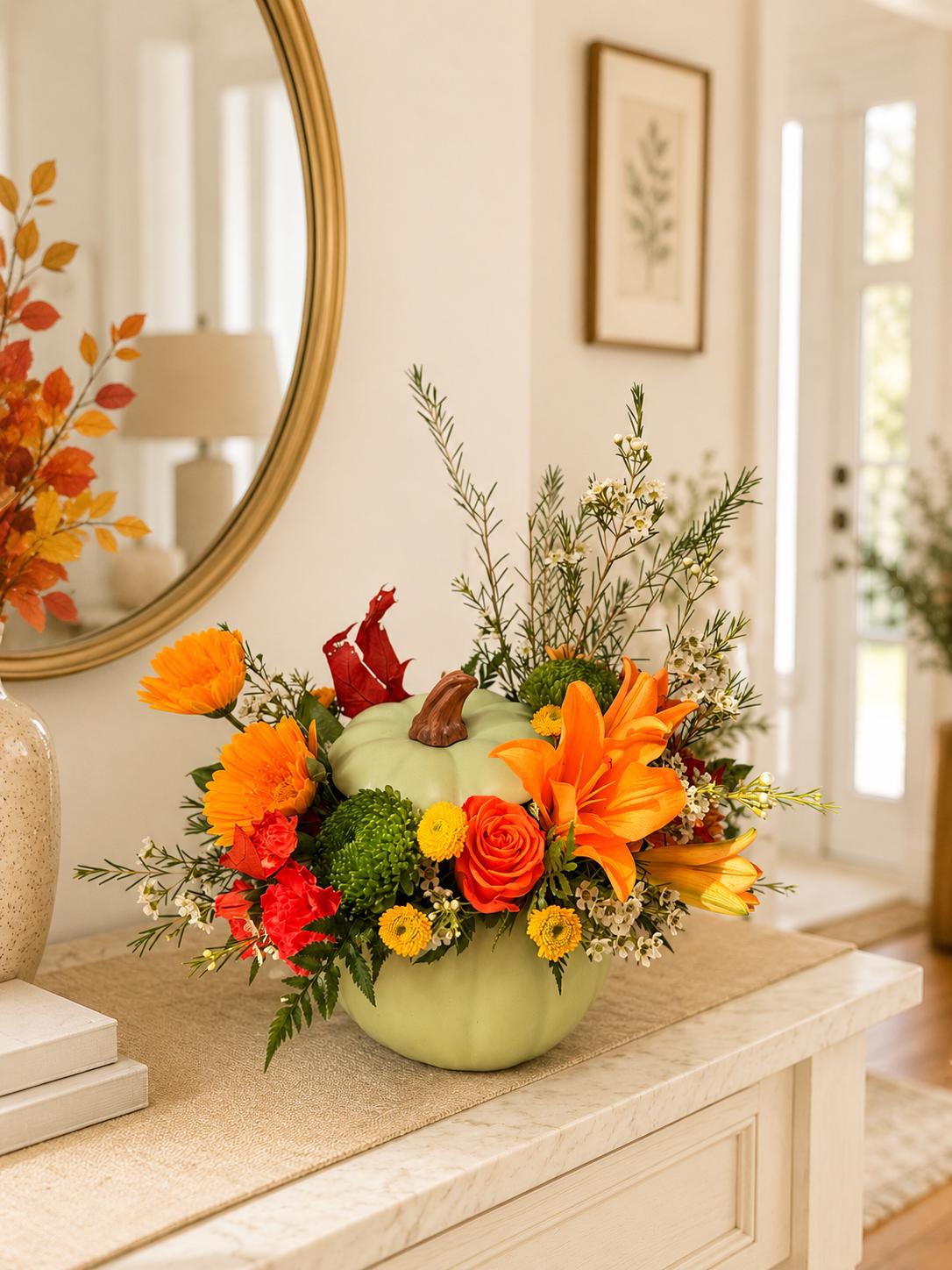 Pumpkin-shaped floral arrangement with orange and red blooms in a vase