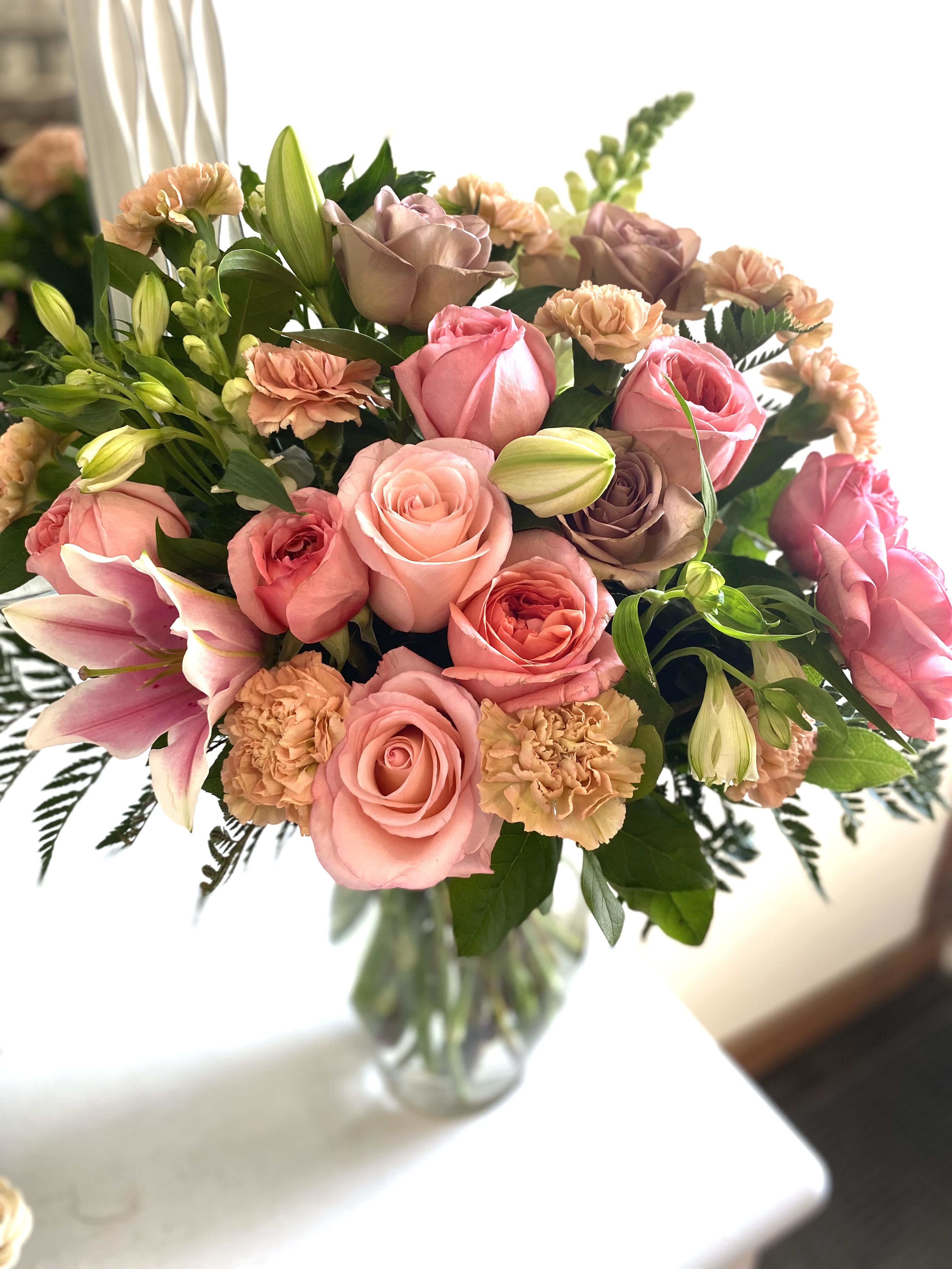 Timeless - A timeless and elegant bouquet, perfect for any occasion. Soft pink and peach roses blend beautifully with delicate lilies and sweet carnations, while lush greenery adds depth and freshness. This stunning arrangement is a perfect way to express love, appreciation, or simply brighten someone's day with its graceful charm.