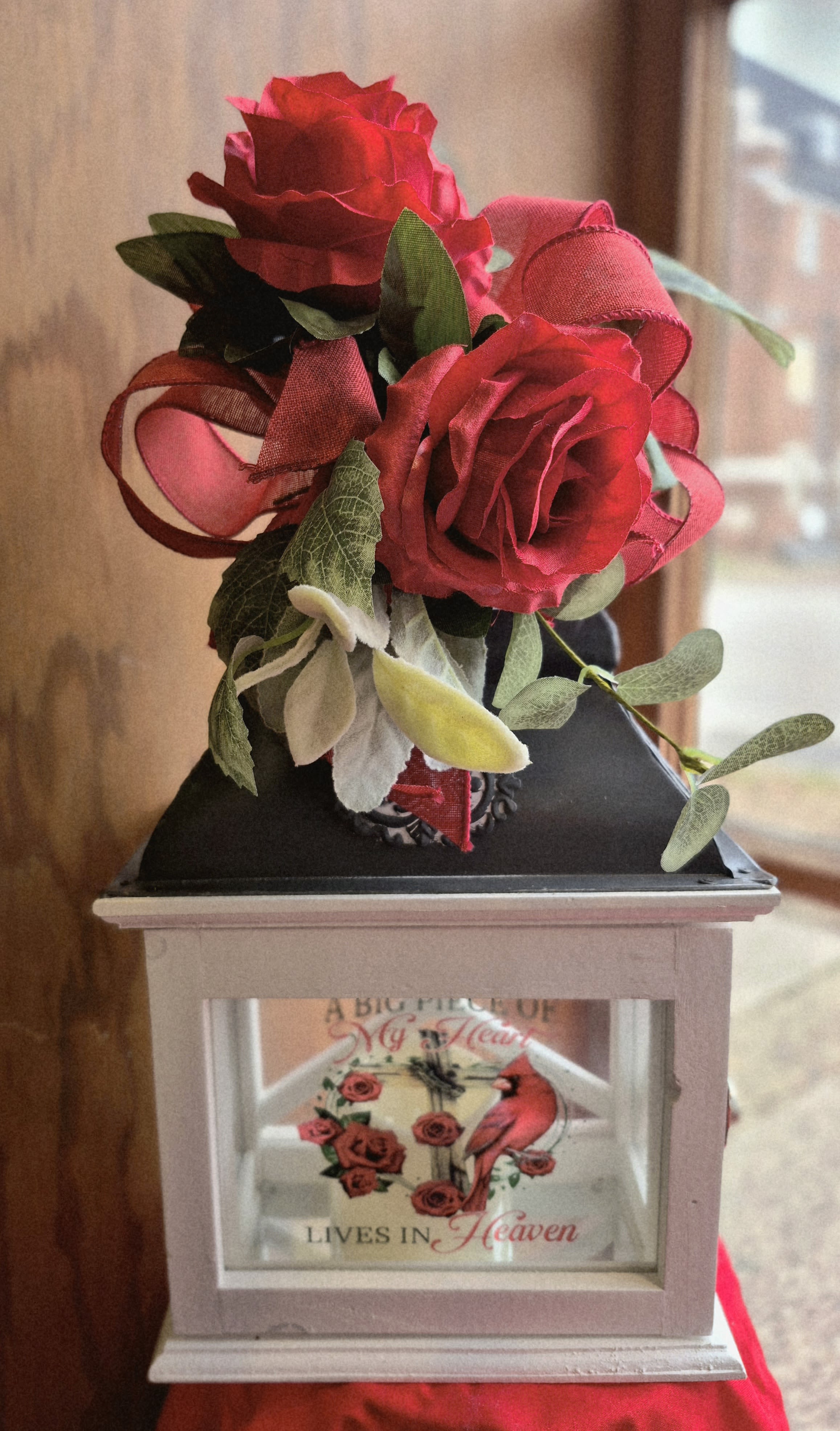 Red roses arranged on a memorial lantern with a framed tribute panel