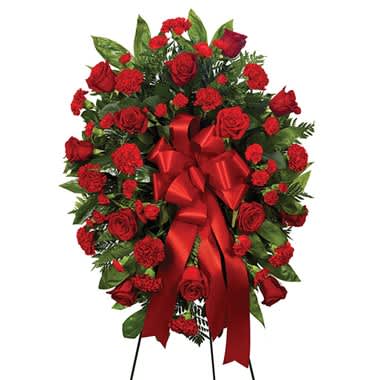 Red rose and carnation standing spray with a red ribbon