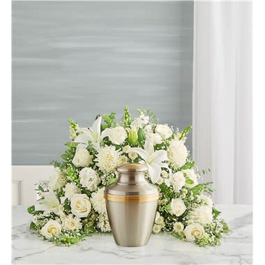 White floral funeral arrangement with an urn in front