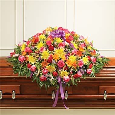 Large colorful floral casket spray with a purple ribbon