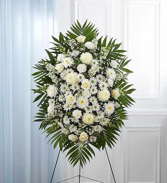 White funeral spray with daisies and roses on an easel