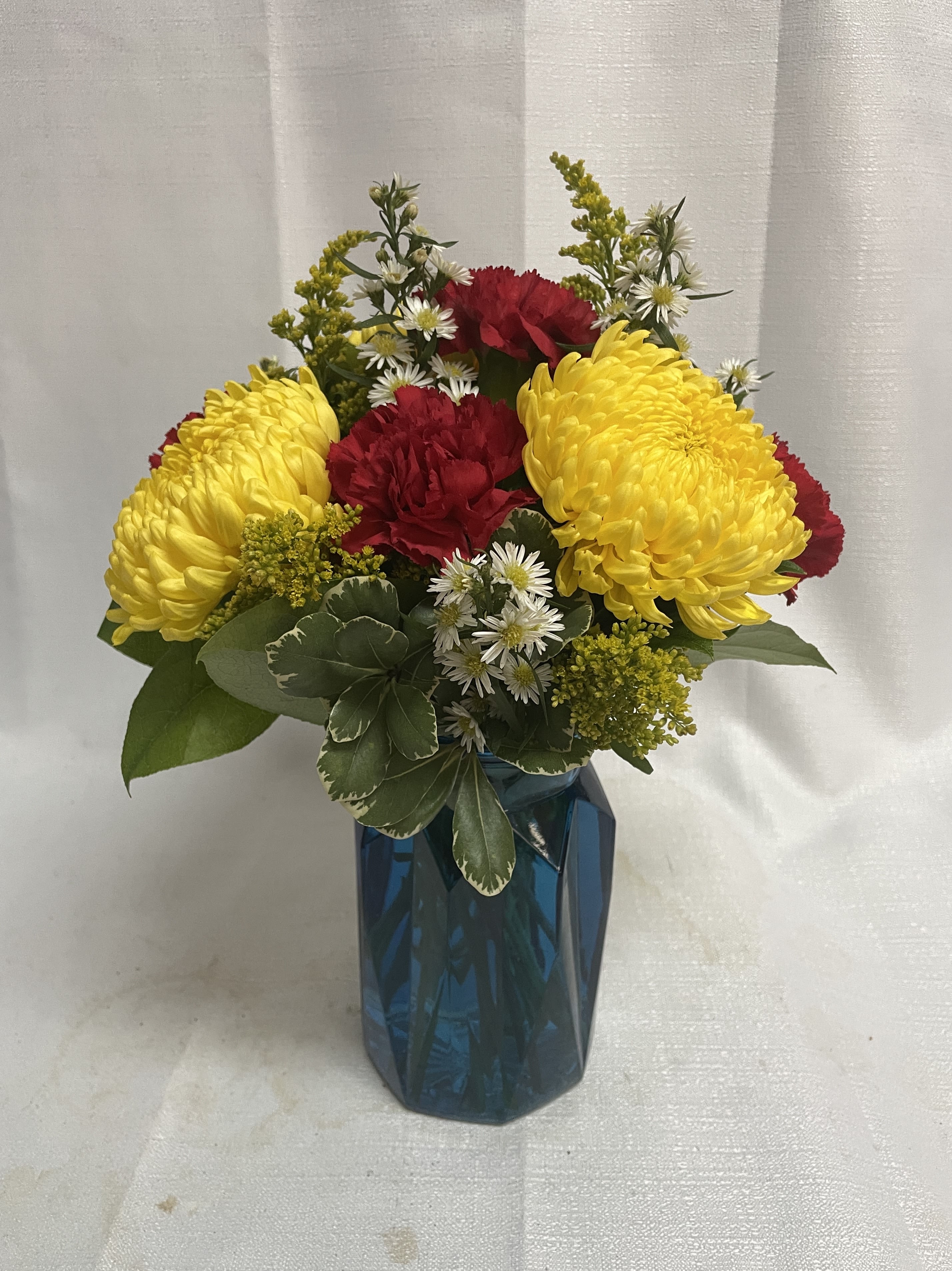 Yellow and red flowers arranged in a blue vase