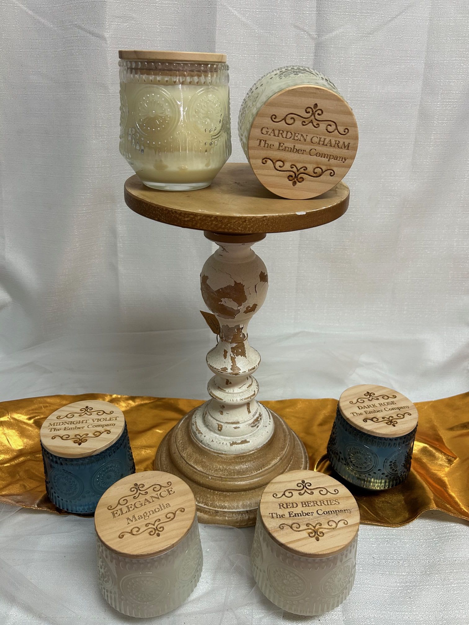 Assorted scented candles in glass jars on a decorative pedestal stand
