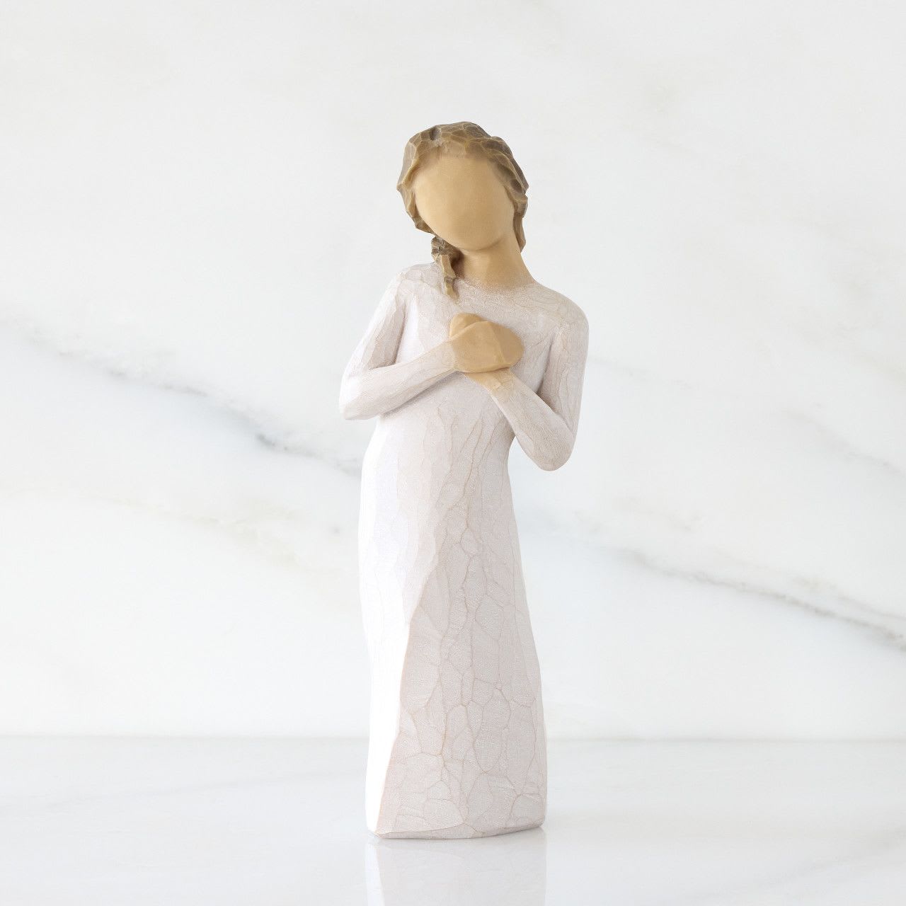 Willow Tree-Here for You - A small, serene sympathy arrangement centered around a softly carved angel figurine-perfect for sending comfort after a loss or as a thoughtful memorial accent. This flower arrangement for sympathy combines gentle whites and soft pinks to create a peaceful, devotional gift that lets the person you're thinking of know you care. The angel's faceless, long white dress and hands folded over the chest set a quiet, reflective tone that reads as both comforting and timeless.  The blooms are arranged to complement the pale finish of the angel, with white flowers to symbolize peace and pink accents to offer warmth and tenderness. The compact size makes this piece suitable for a bedside table, mantel, or memorial service display; it's designed to be a keepsake that can remain after the flowers fade. For someone who needs a quiet reminder that they're not alone, this arrangement delivers a gentle message of support and remembrance.