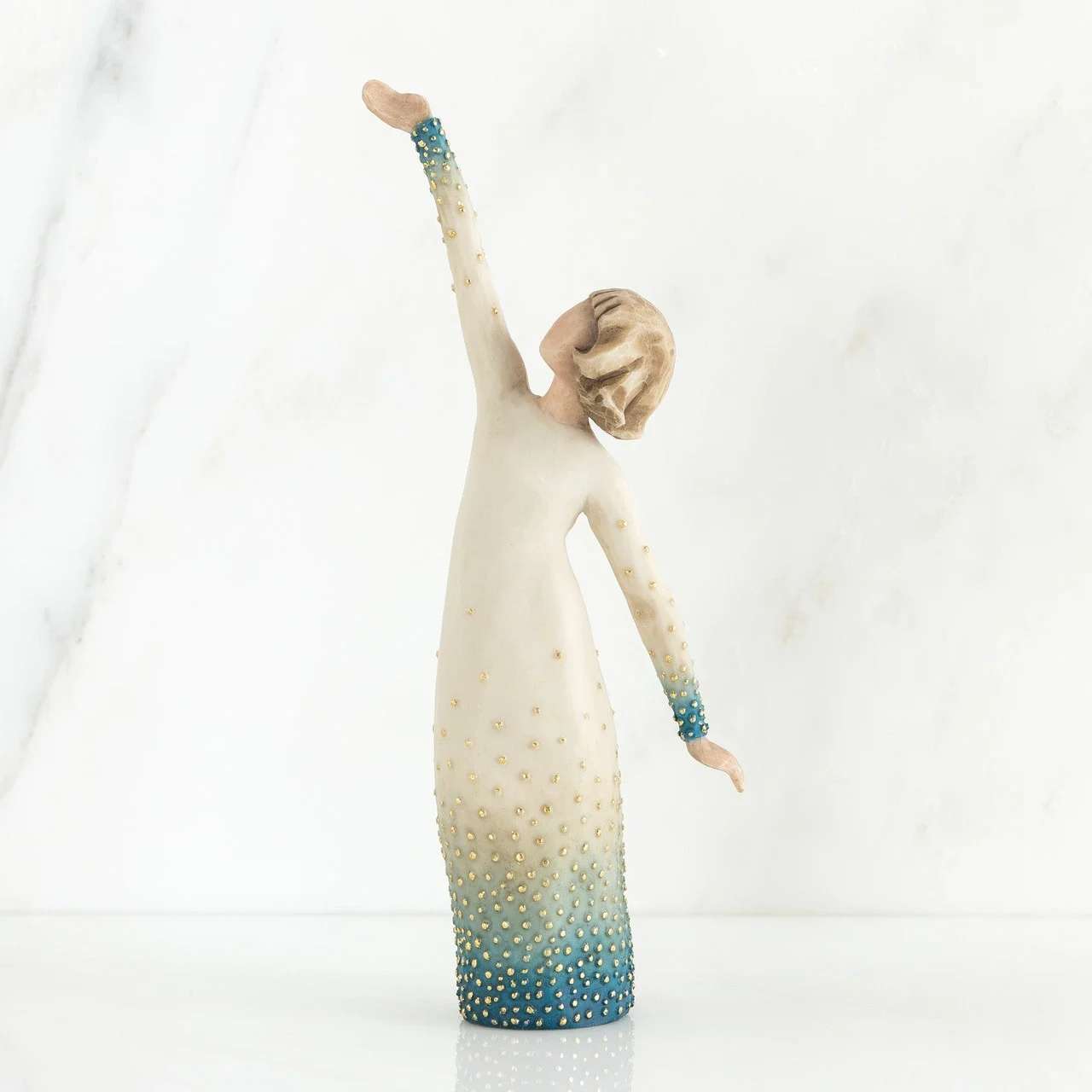 Willow Tree Shine - This porcelain-style decorative figurine captures a serene, elongated woman in a long cream dress that fades to blue at the hem and cuffs-an elegant keepsake gift perfect for Mother's Day, a birthday, or a thoughtful just-because present. As a home décor accent rather than a cut-flower arrangement, it brings quiet, artistic charm to a mantel, bedside table, or entry console and will make the person you're thinking of feel gently celebrated and seen.  The figure's cream-to-blue ombré glaze, delicate dotted embellishments, and graceful pose create soft visual texture and a calm palette of white, blue, and neutral tones that fit coastal, modern, or cottage-style interiors. Sized for display (hand-held scale in photos), the piece is designed to stand on its own as a sentimental decorative accent and pairs well with other keepsakes or a small bouquet placed beside it.  Gift this to a mom, friend, or partner who treasures handcrafted-style décor and subtle symbolism; it's the kind of present that stays on display as a lasting reminder of your thoughtfulness. No special care is required for the figurine-dust gently with a soft cloth-and it ships ready to gift for easy presentation.
