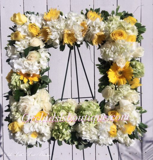 Square floral wreath with white and yellow flowers on a black stand