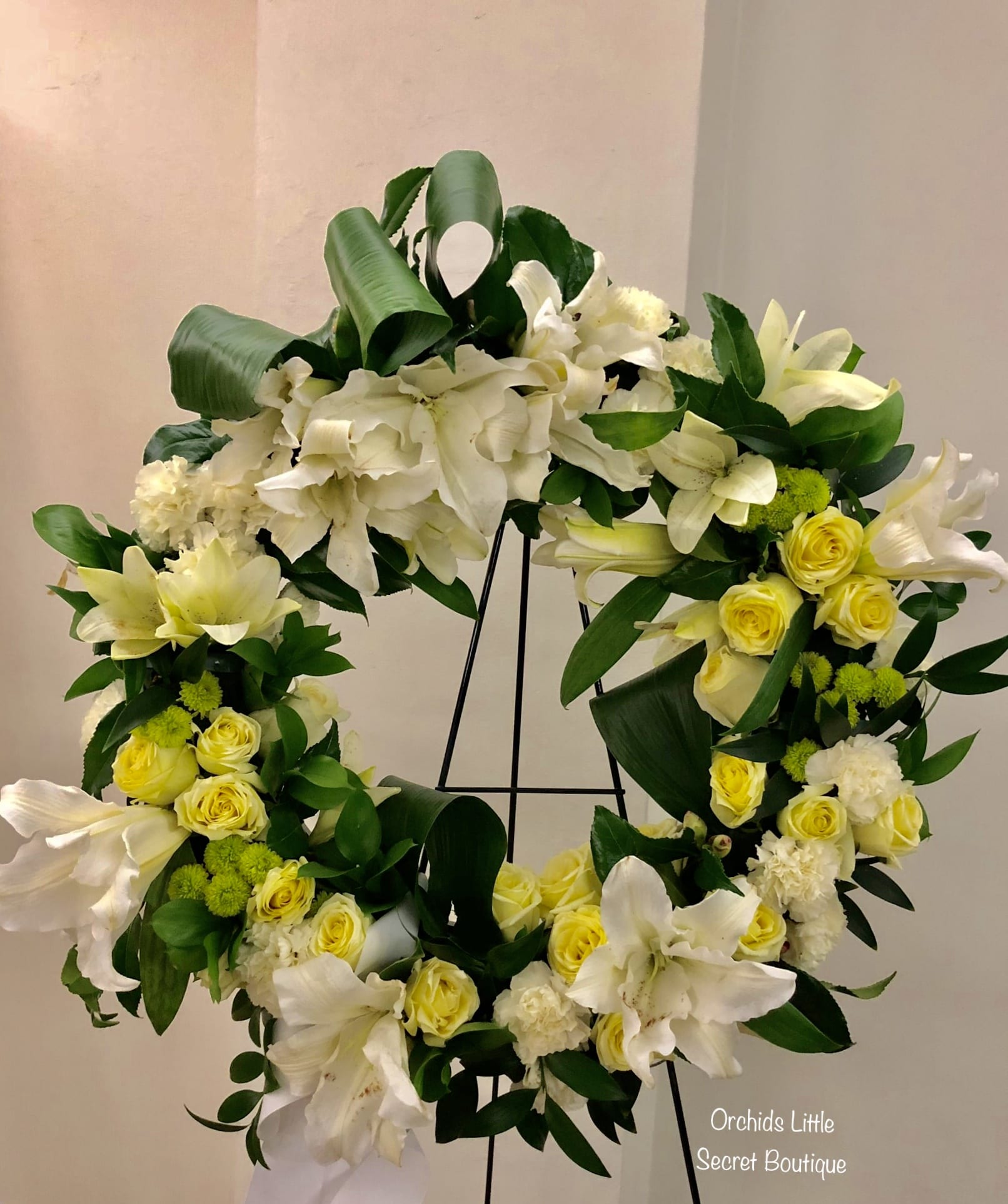 White and yellow floral wreath on a black stand