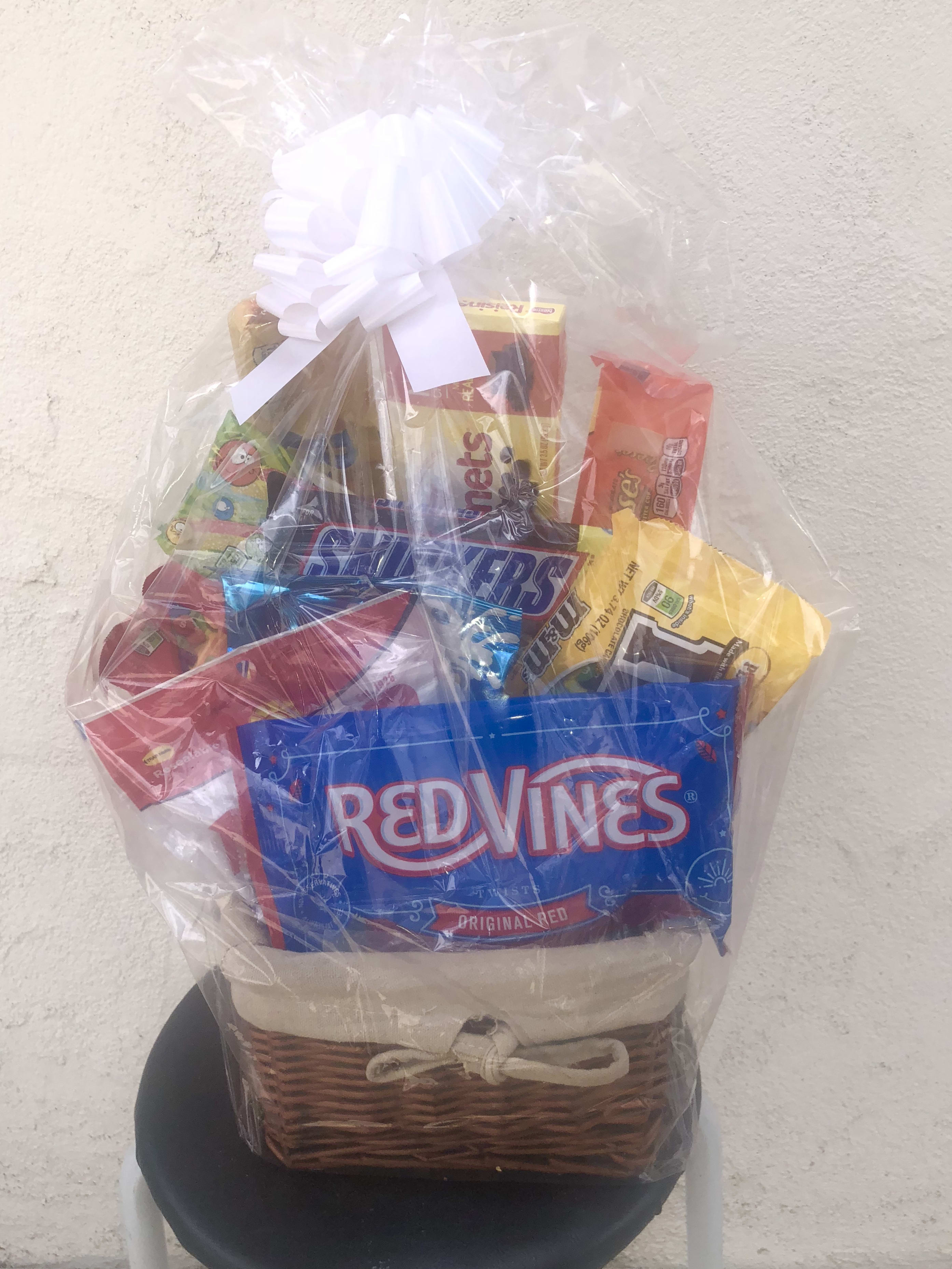Gift basket of assorted candy wrapped in clear cellophane with a white bow