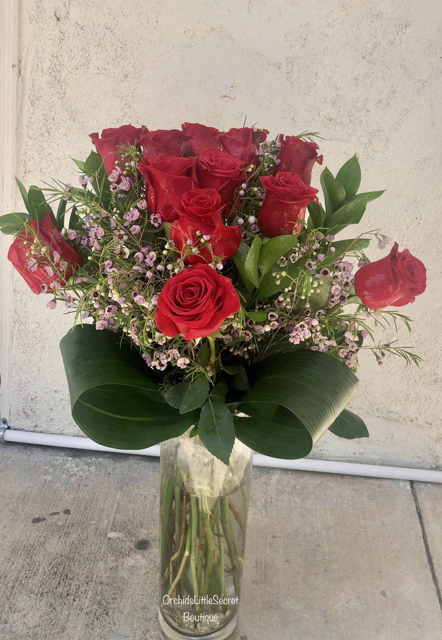Bouquet of red roses with pink filler flowers in a clear glass vase