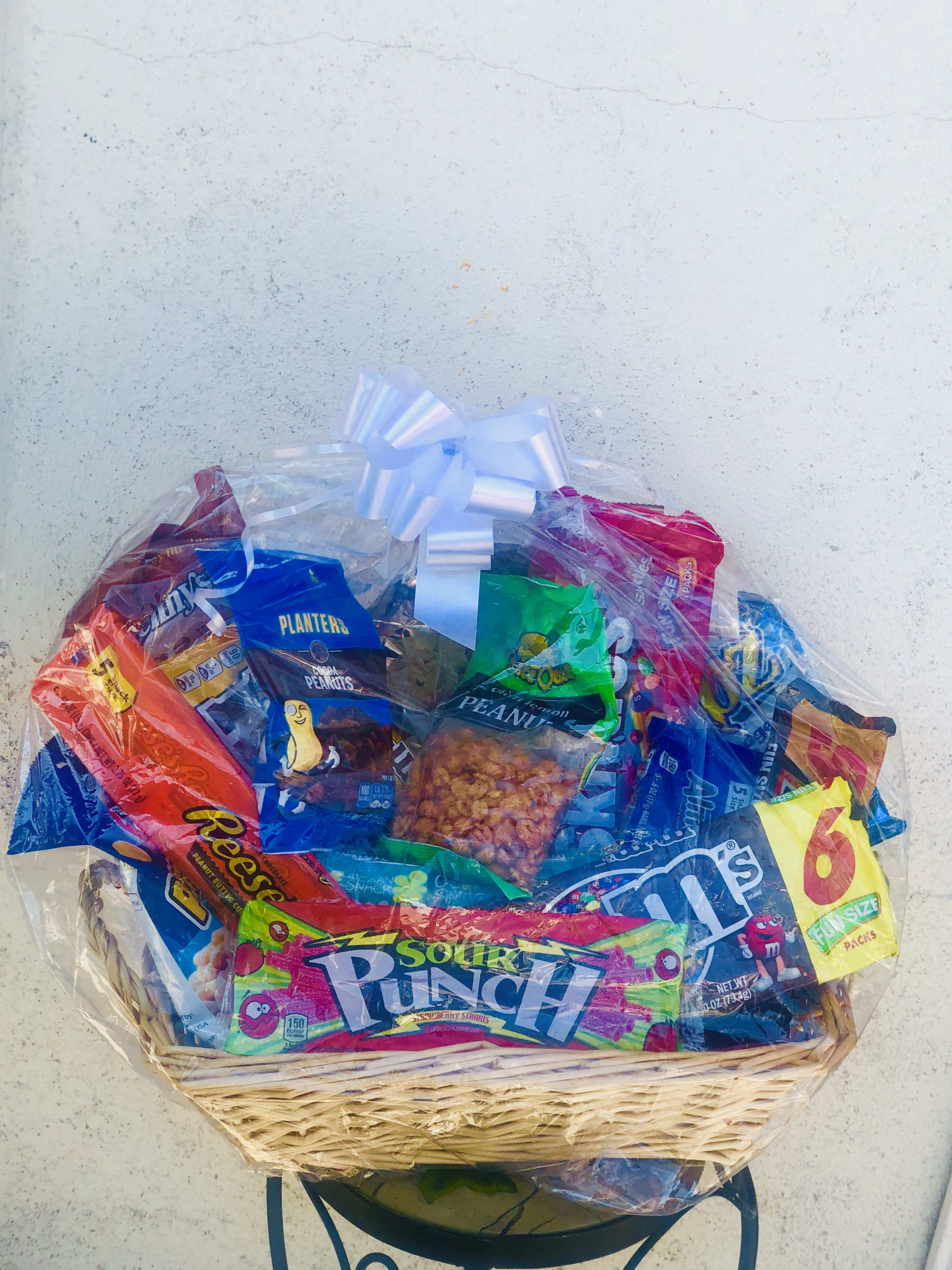 Basket of assorted snack bags wrapped in clear cellophane with a white bow