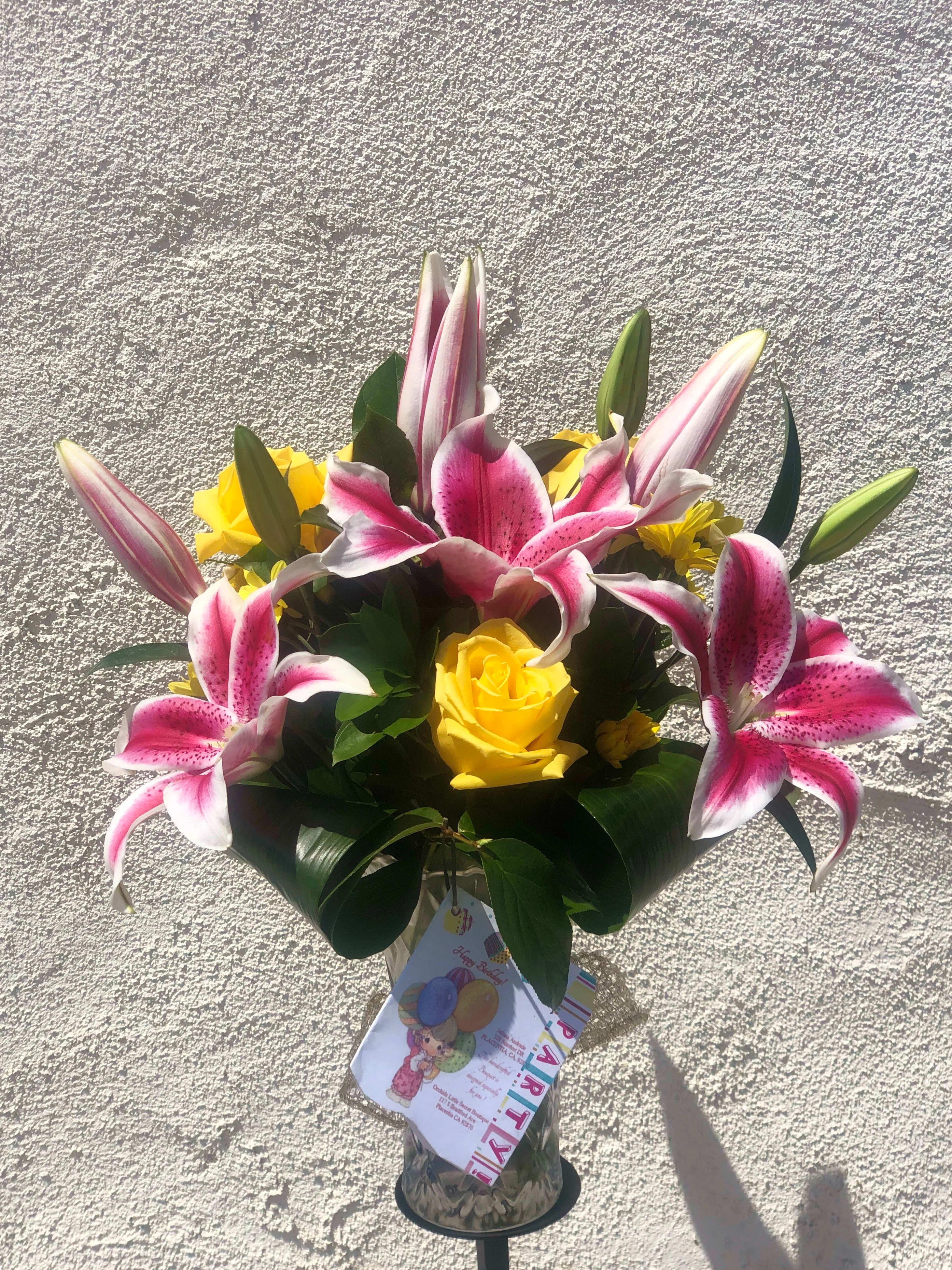 Bouquet of pink lilies and yellow roses in a glass vase