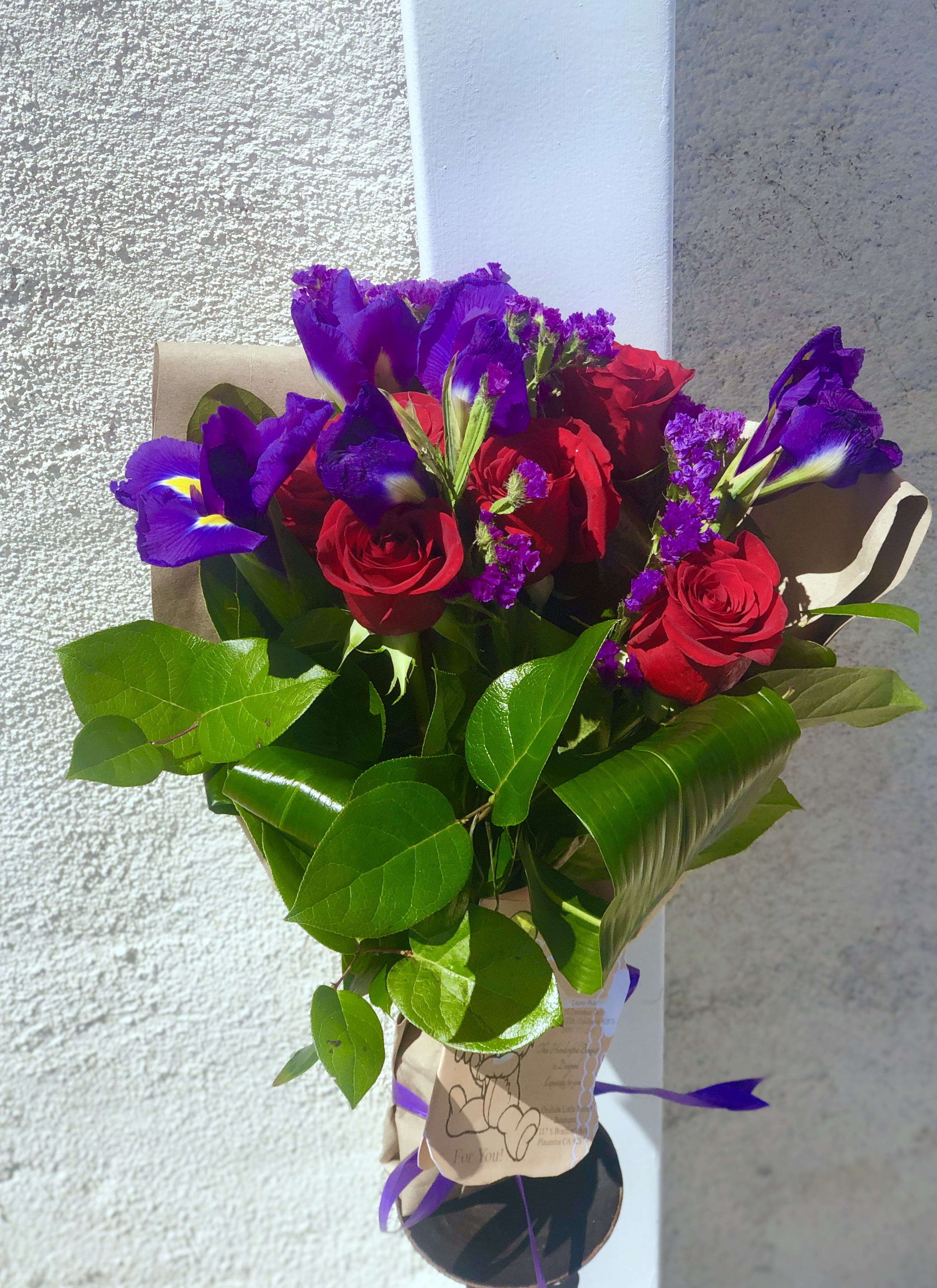 Bouquet of red roses and purple irises wrapped in brown paper