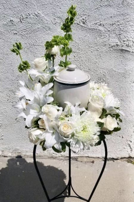 White Cremation Wreath  - This Wreath encircles an urn (not included) This table wreath is open at the center to place a photograph or cremation urn as a tasteful tribute. Measures approximately approximately 16"H x 14" Table not included. 