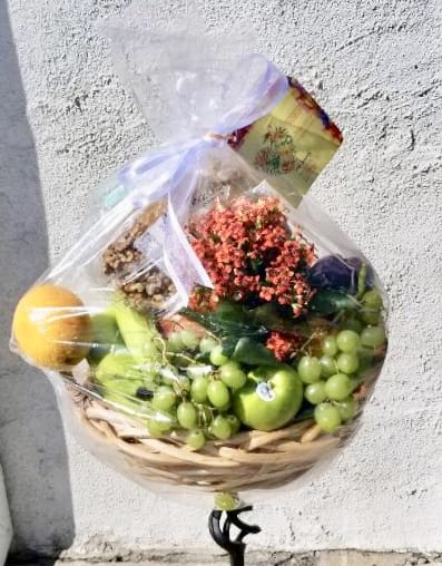 Fruit basket with grapes, apples, and flowers wrapped in clear plastic