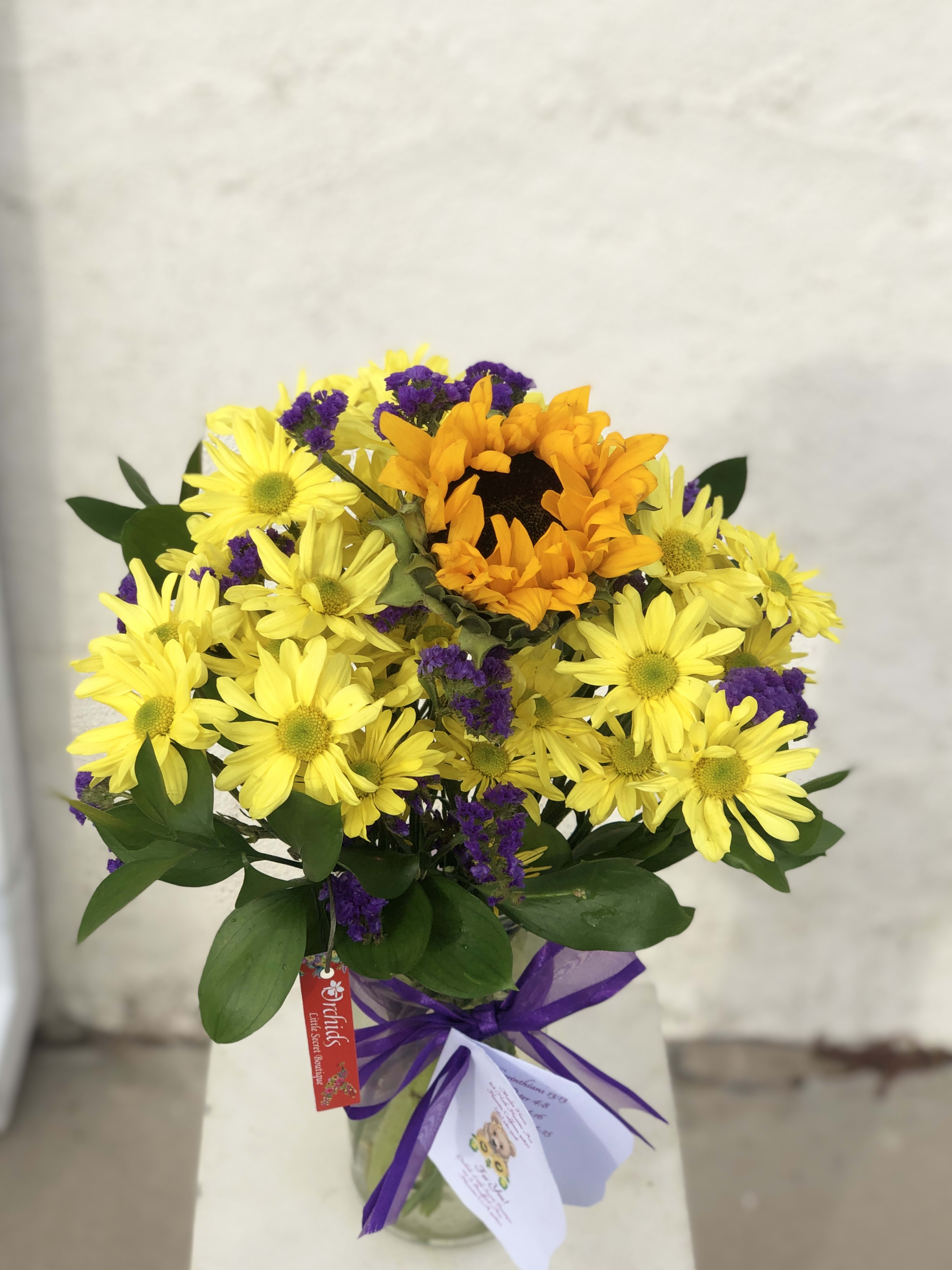 Yellow daisies and an orange sunflower bouquet in a glass vase