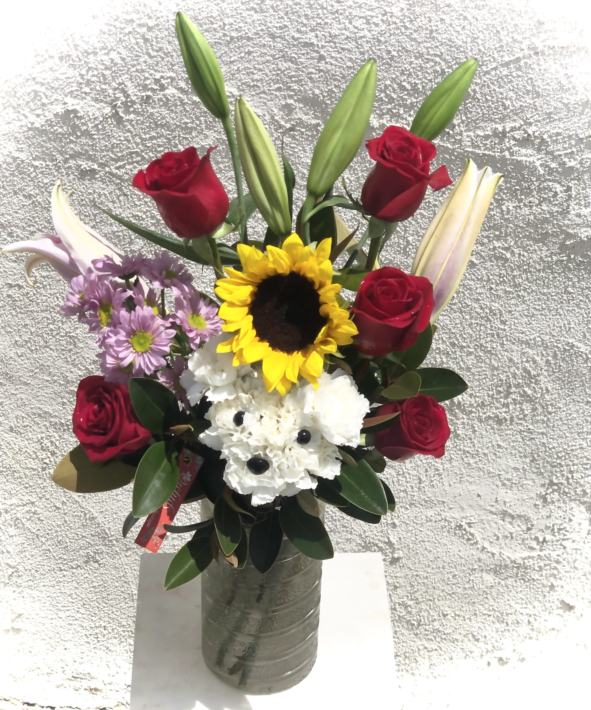 Bouquet of red roses, lilies, sunflowers, and white flowers in a vase
