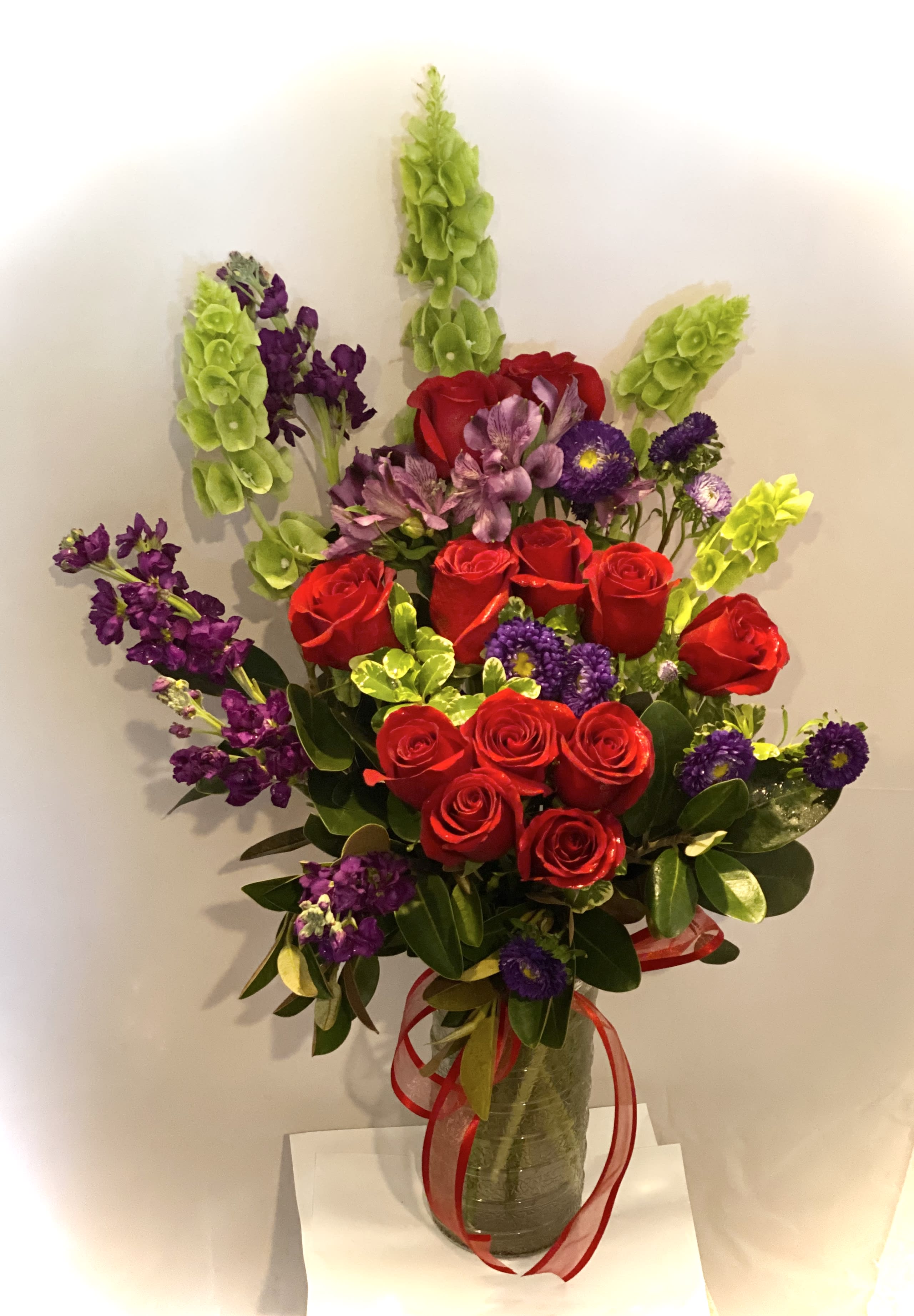 Bouquet of red roses and purple flowers in a glass vase