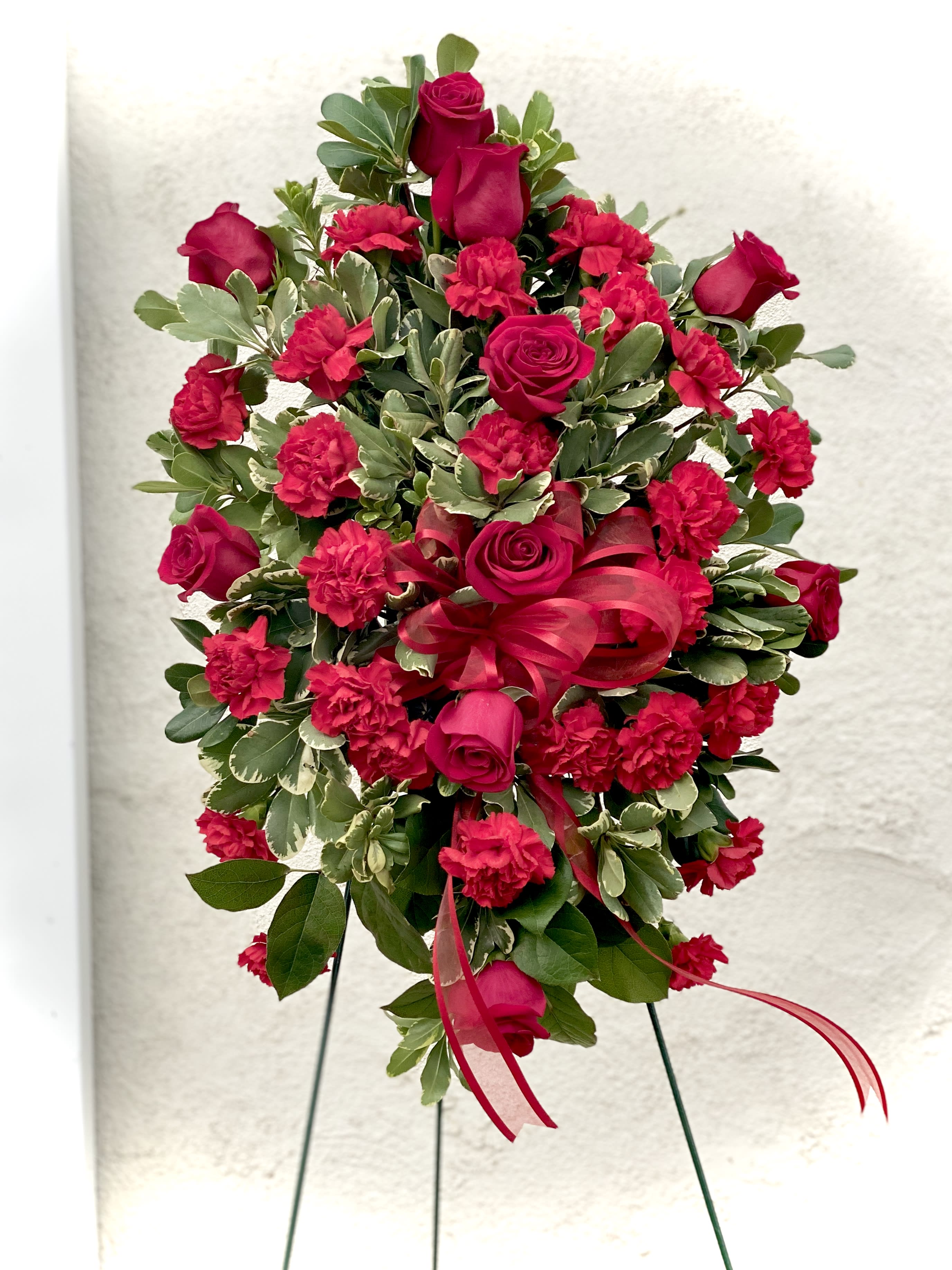 Standing floral spray with red roses and carnations on an easel