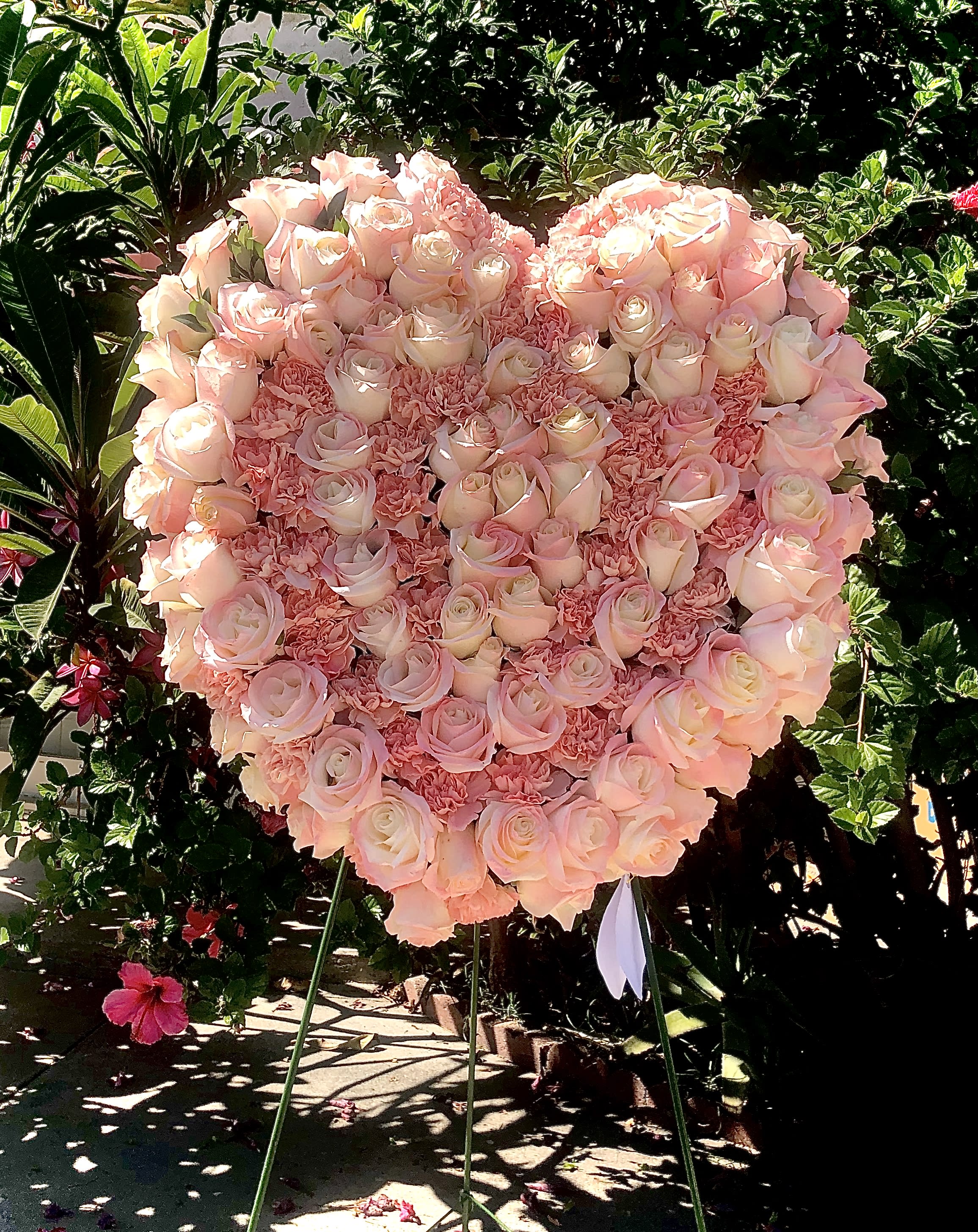 Heart-shaped pink rose and carnation standing spray on a metal easel