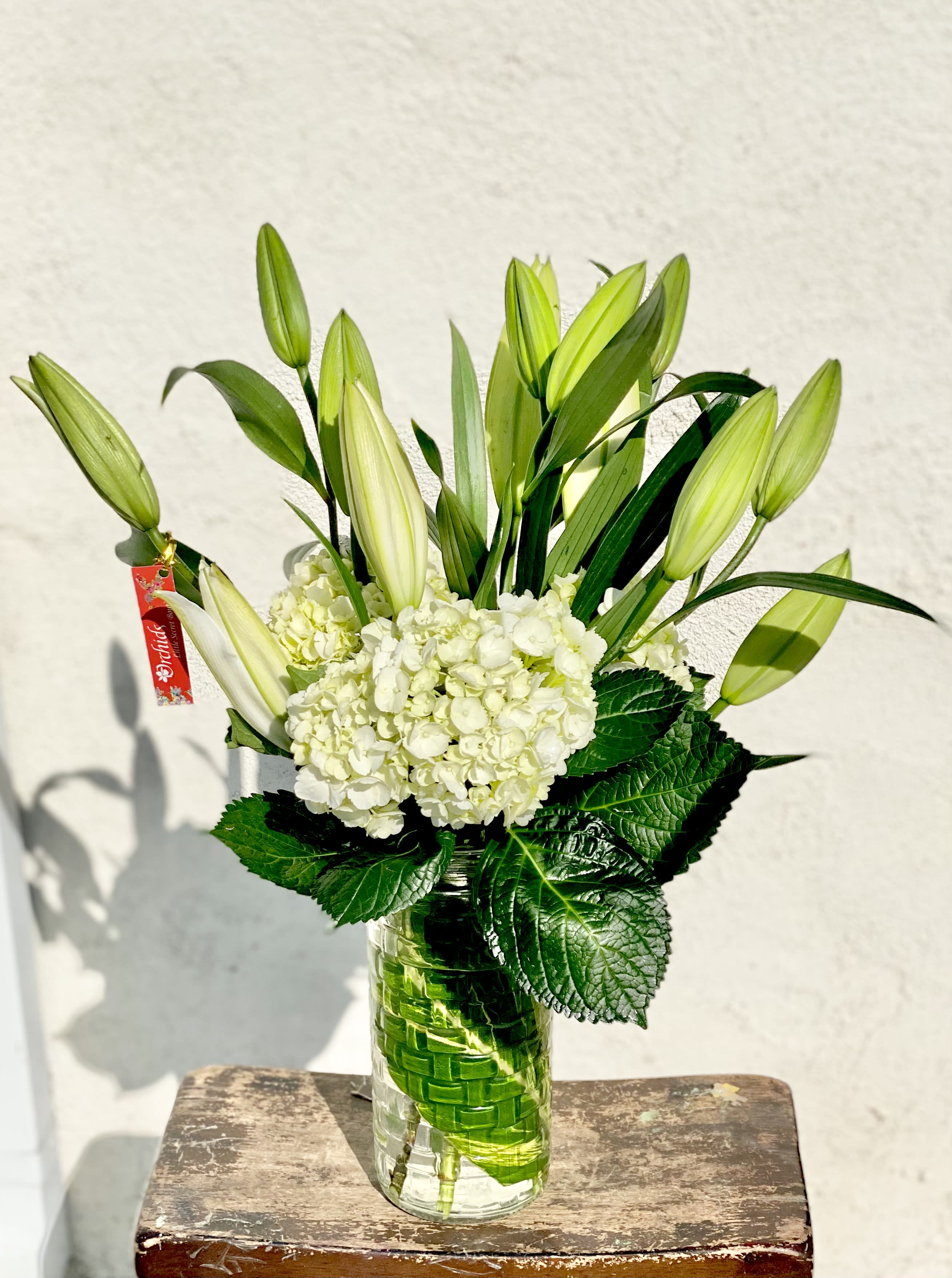 White hydrangeas and unopened lilies in a glass vase