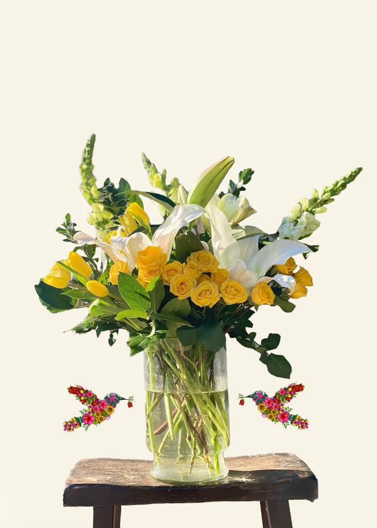 Yellow roses and white lilies in a clear glass vase