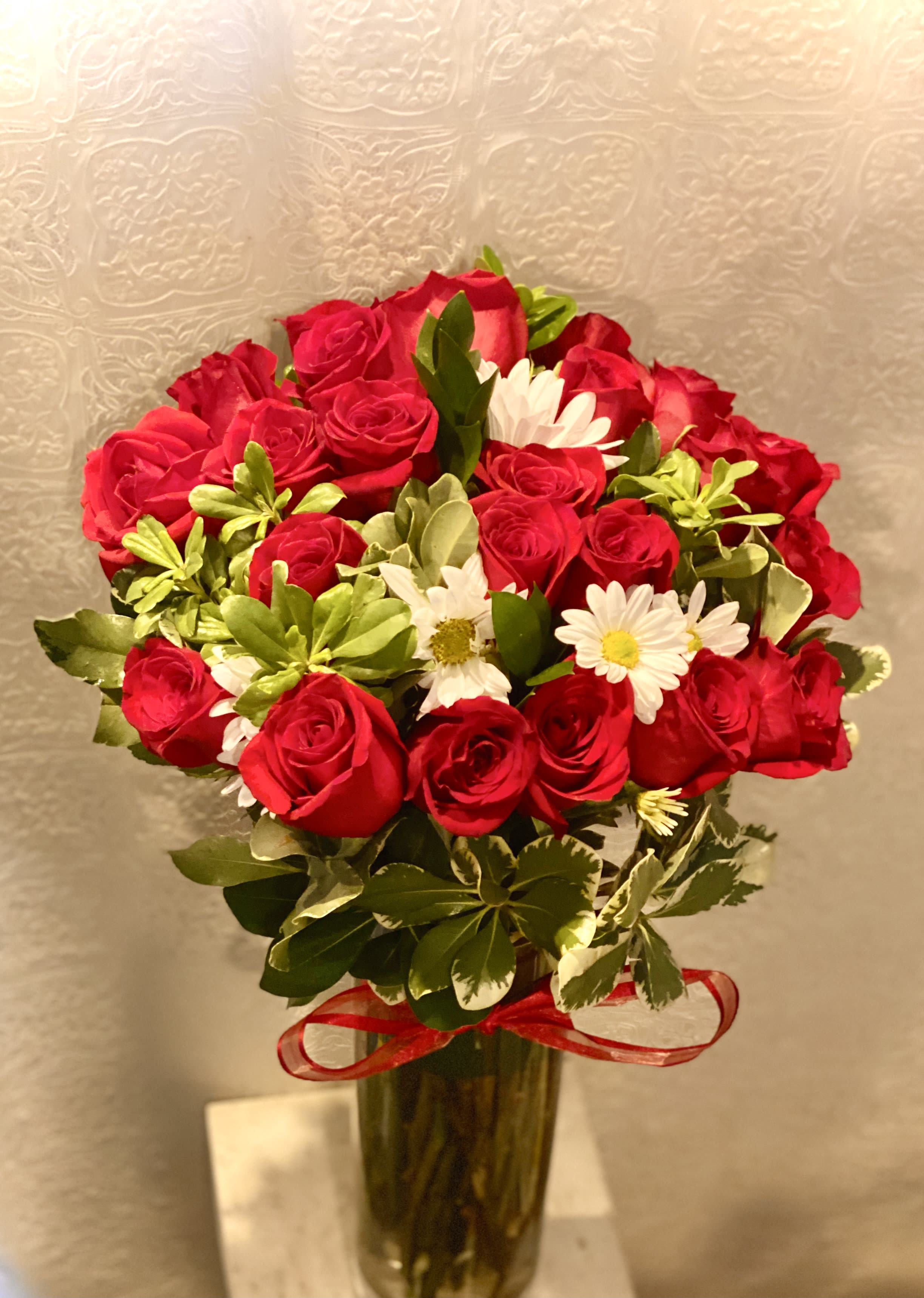 Bouquet of red roses and white daisies in a glass vase