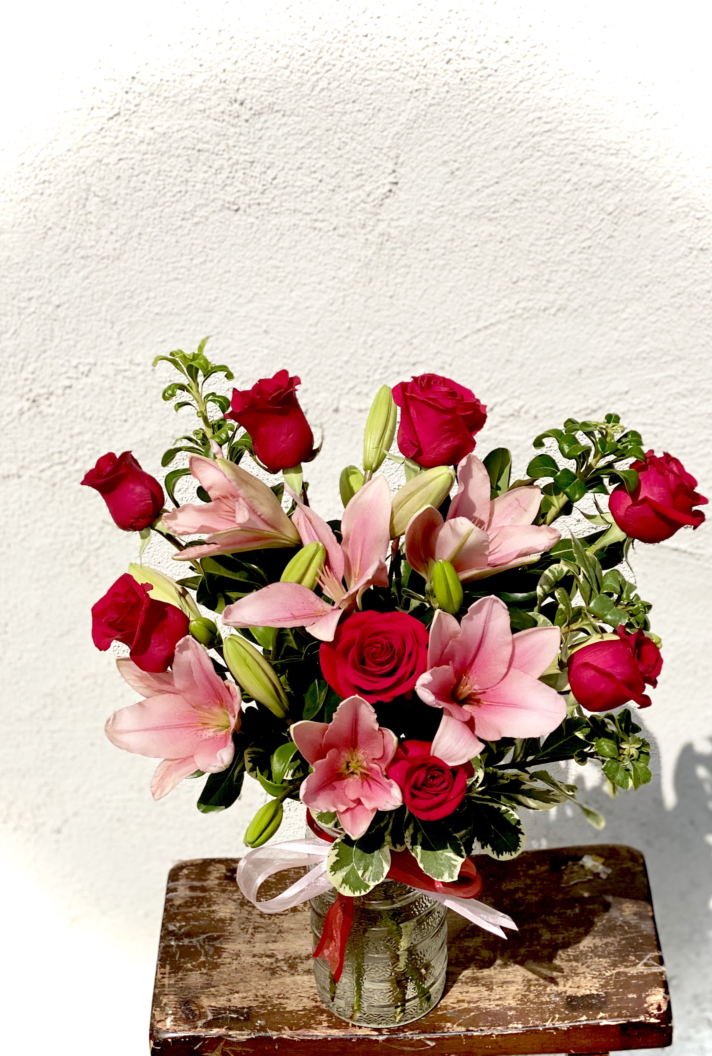 Bouquet of red roses and pink lilies in a glass vase