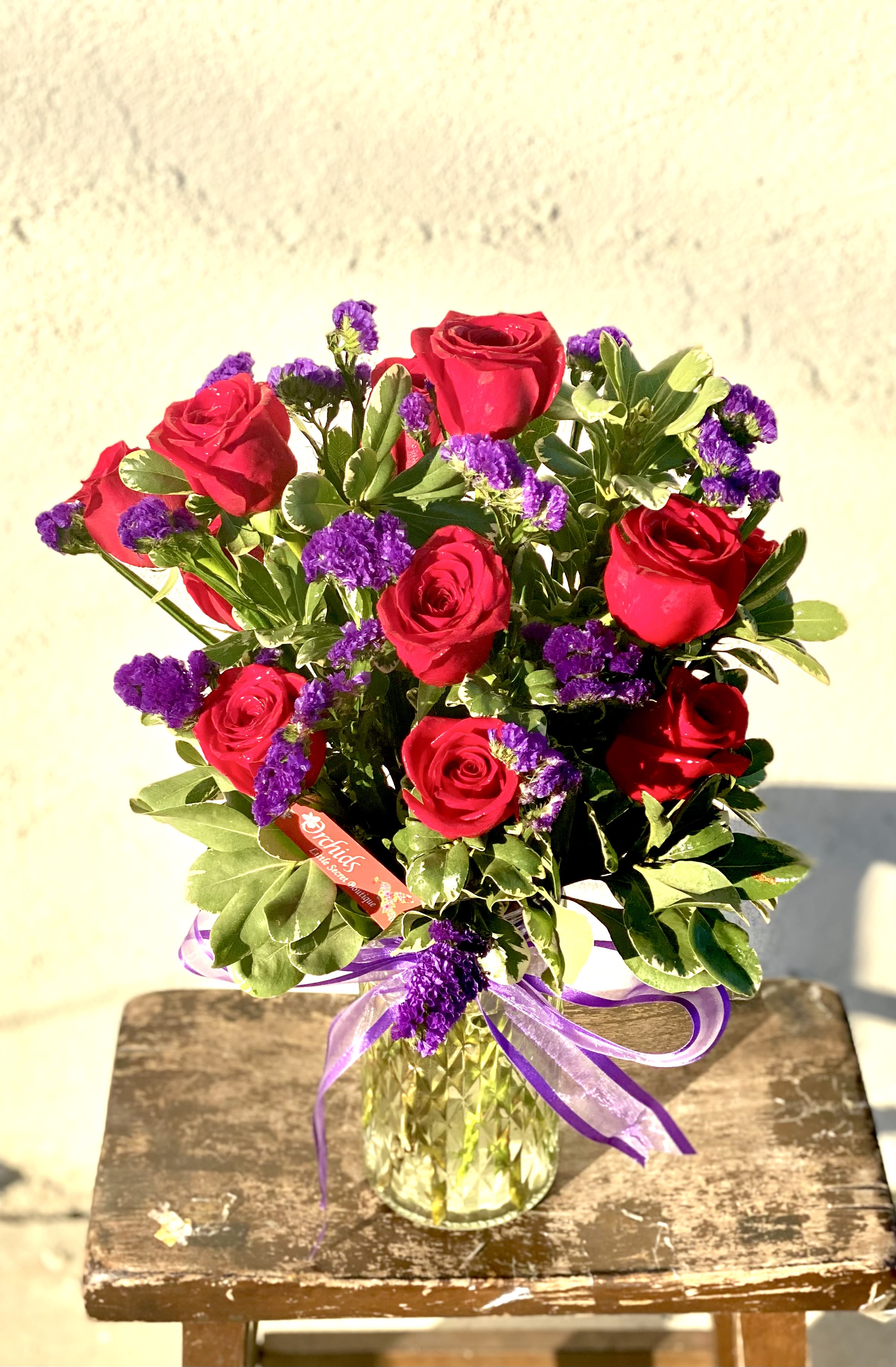Bouquet of red roses and purple filler flowers in a glass vase