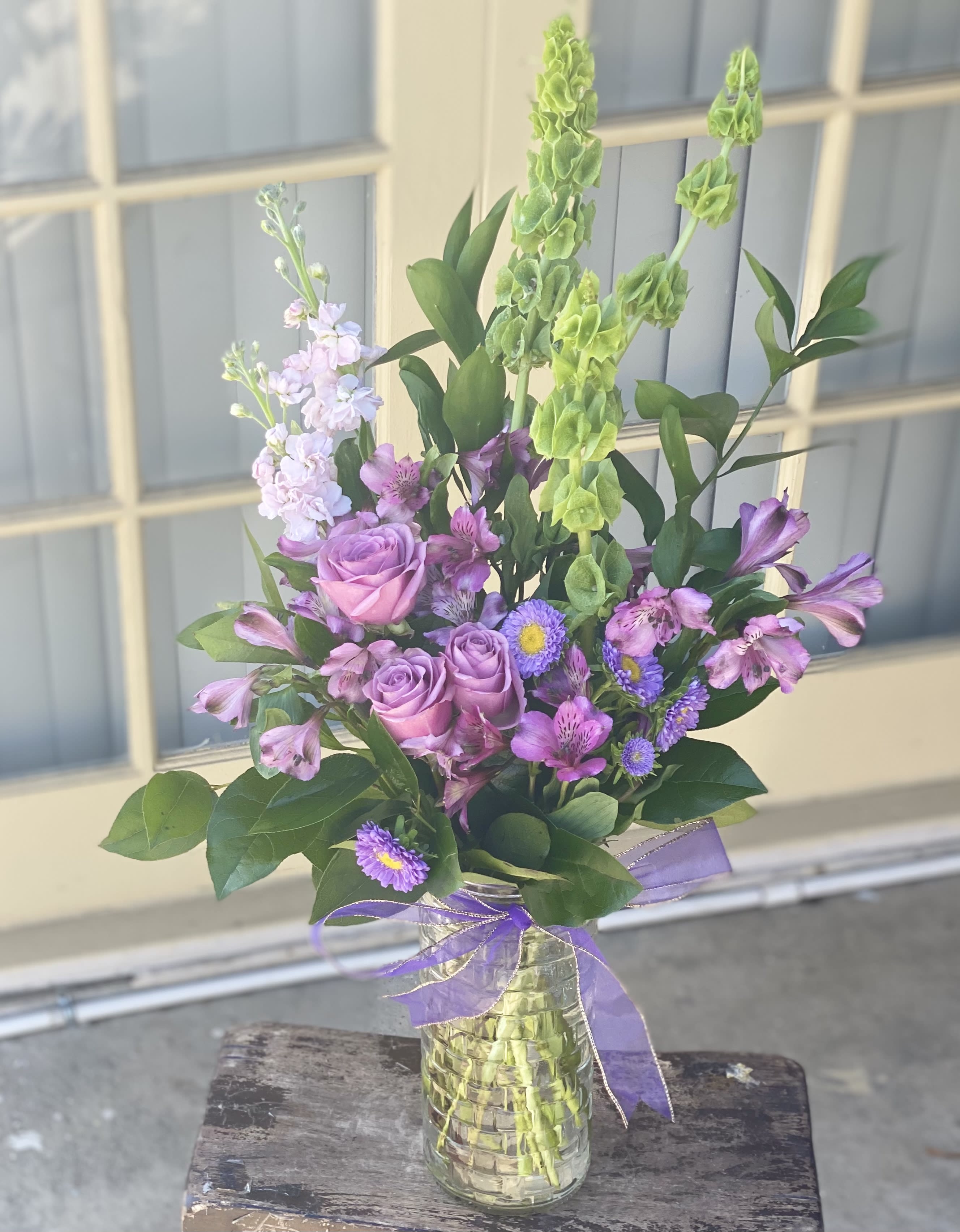 Mixed purple bouquet in a glass vase with a ribbon