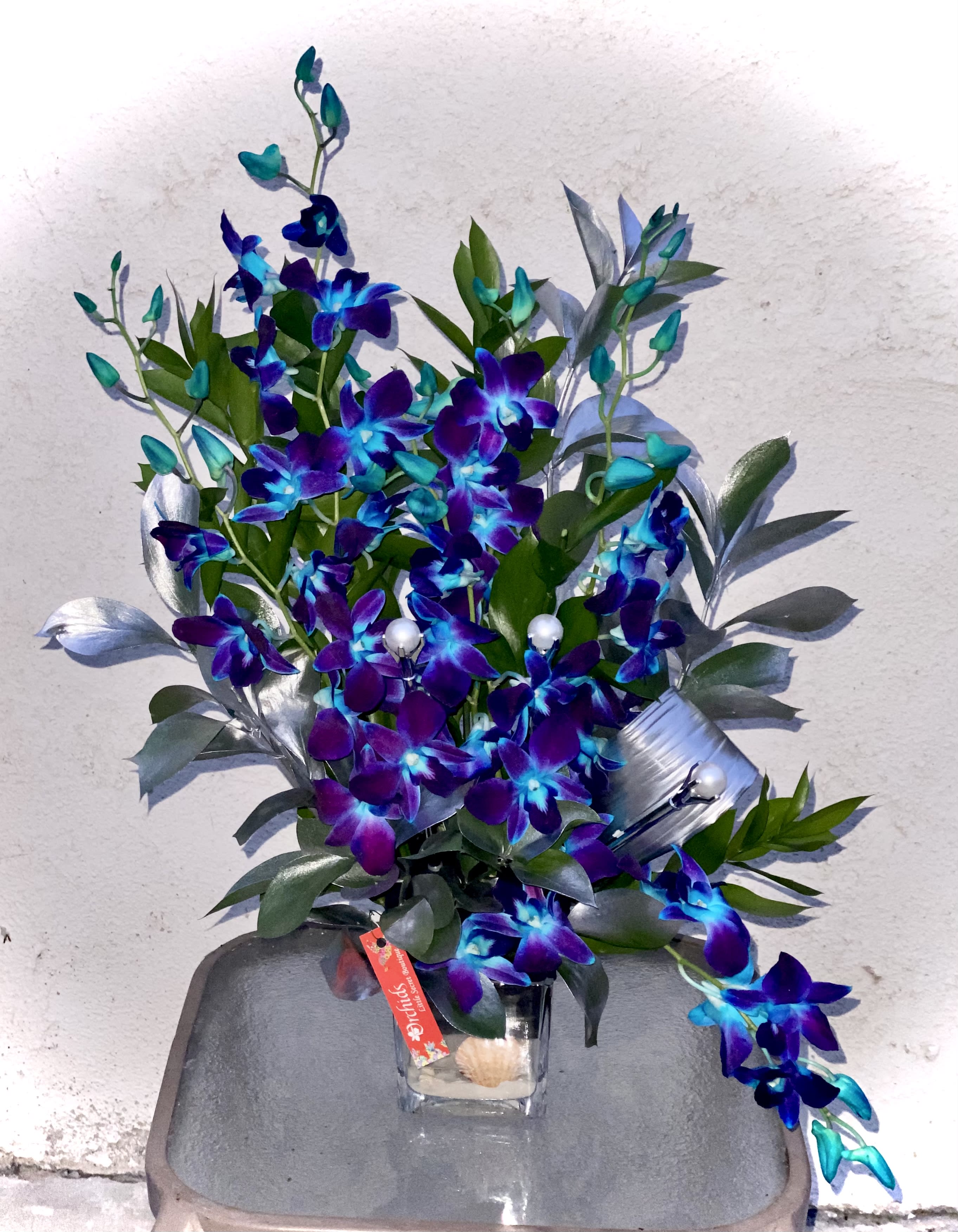 Purple and blue orchid arrangement in a clear glass vase