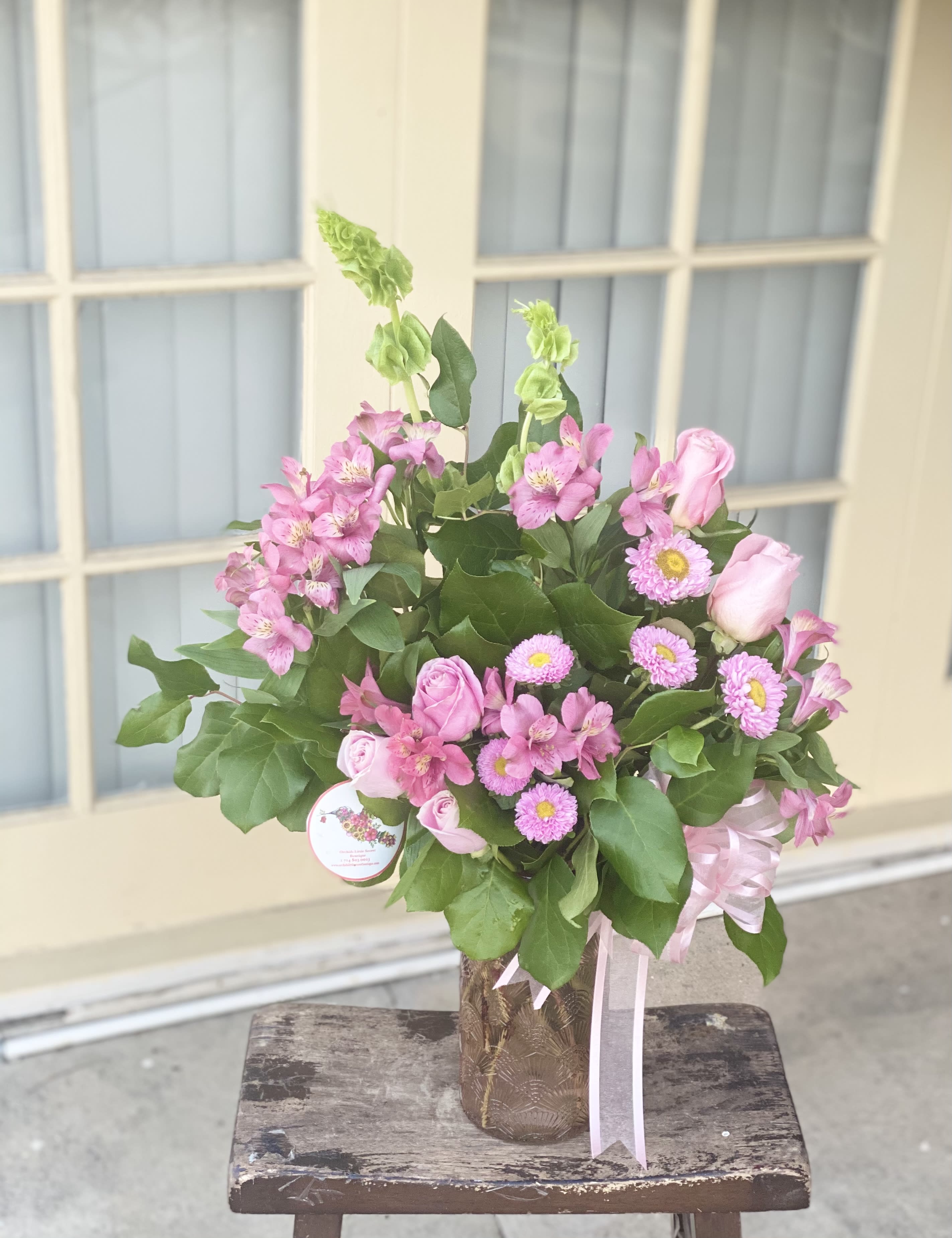Pink roses and alstroemeria in a decorative vase with ribbon