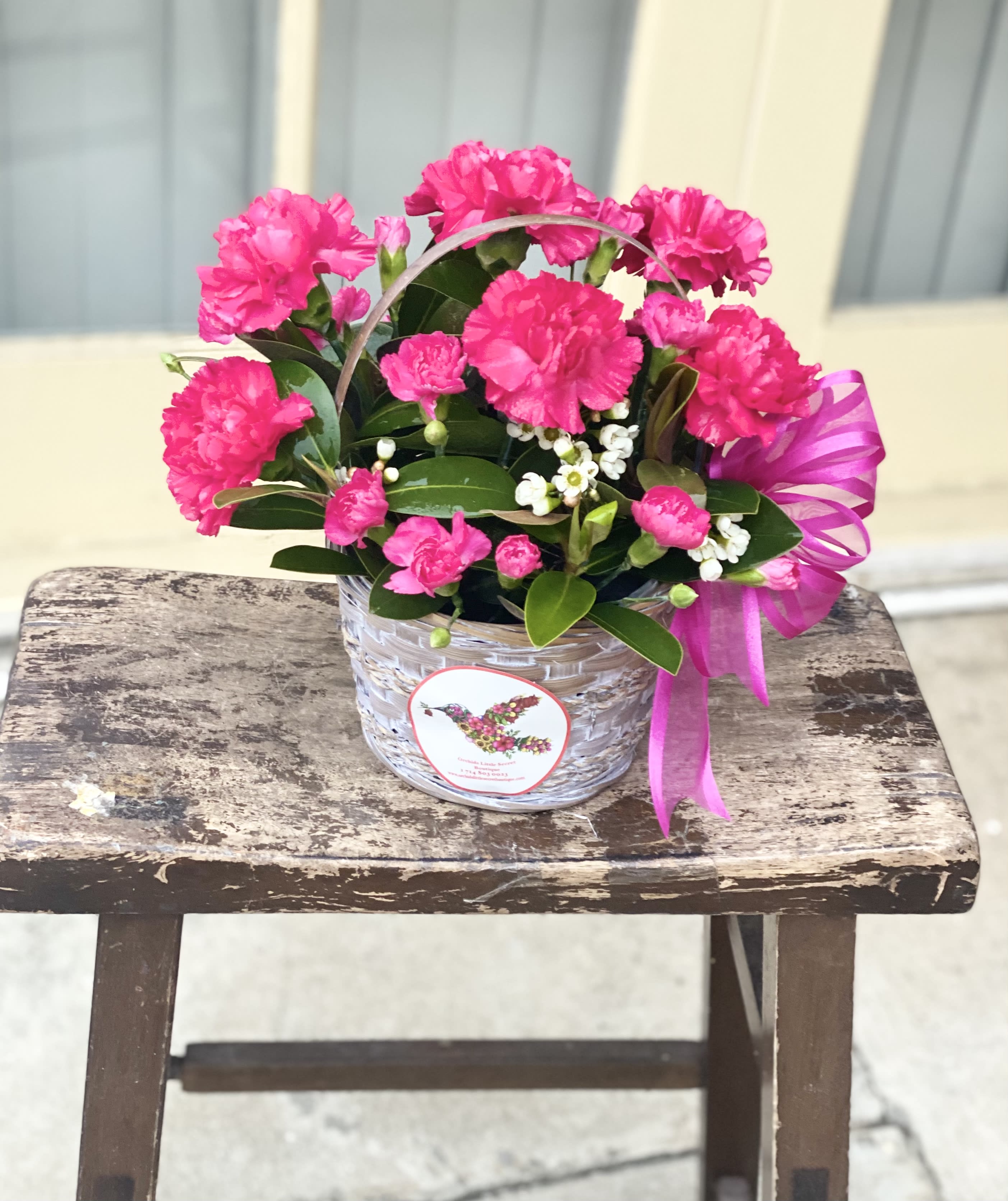 Pink carnations in a woven basket with a ribbon bow
