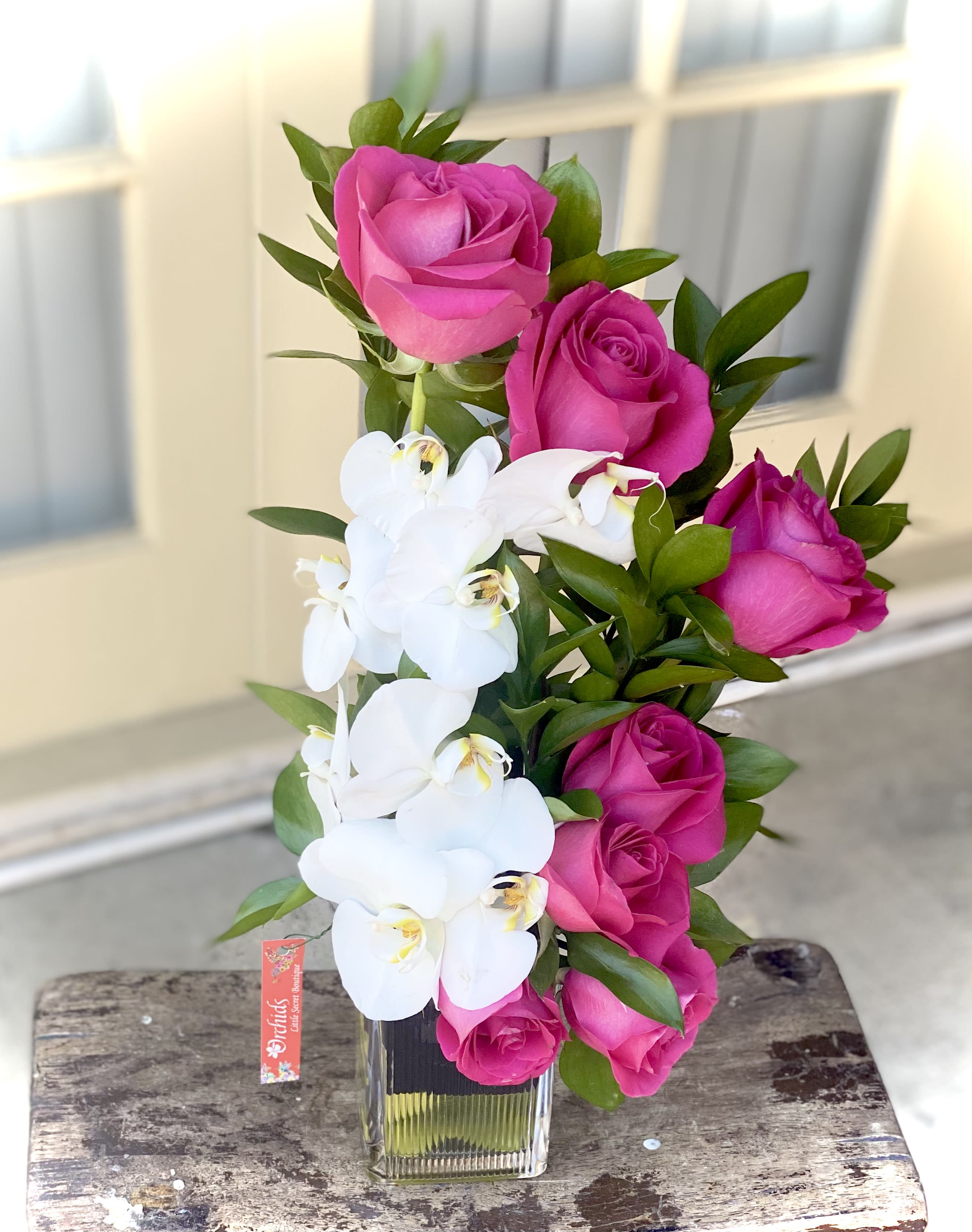Pink roses and white orchids arranged in a clear glass vase.