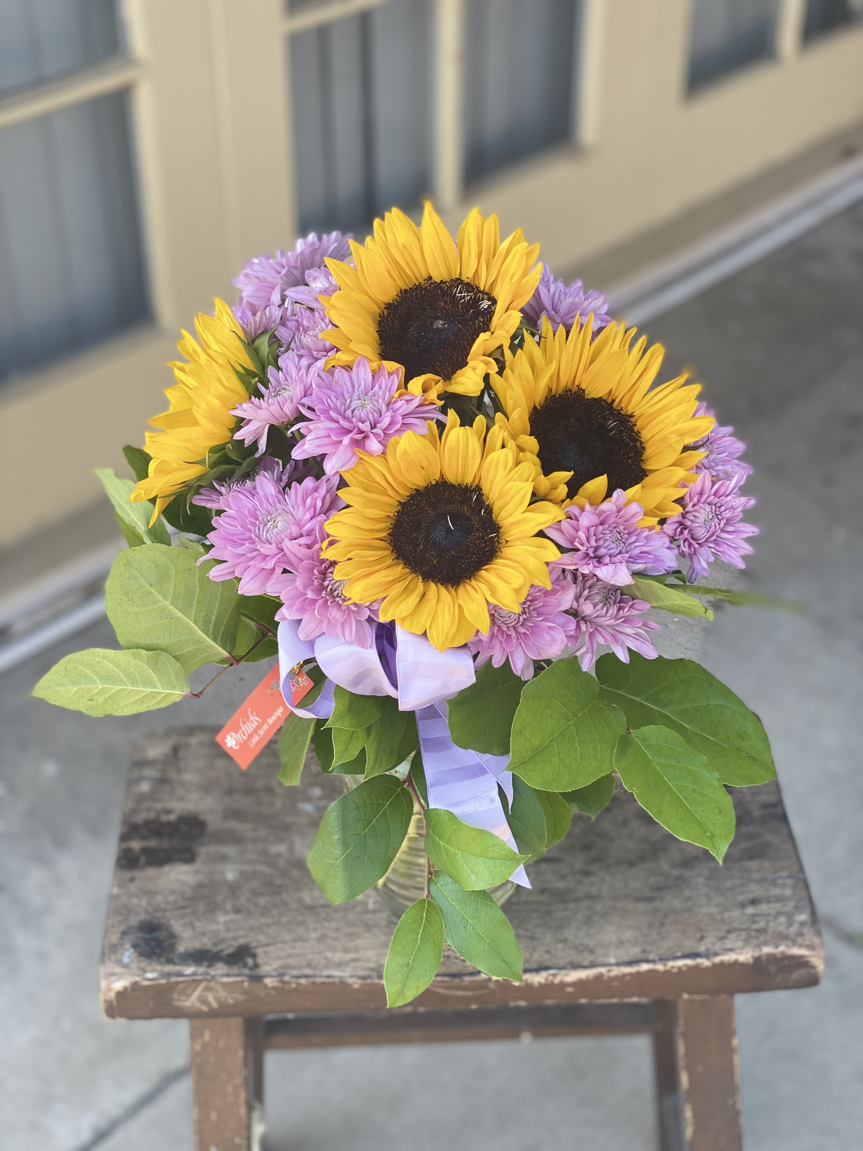 Bouquet of sunflowers and purple chrysanthemums tied with a lavender ribbon