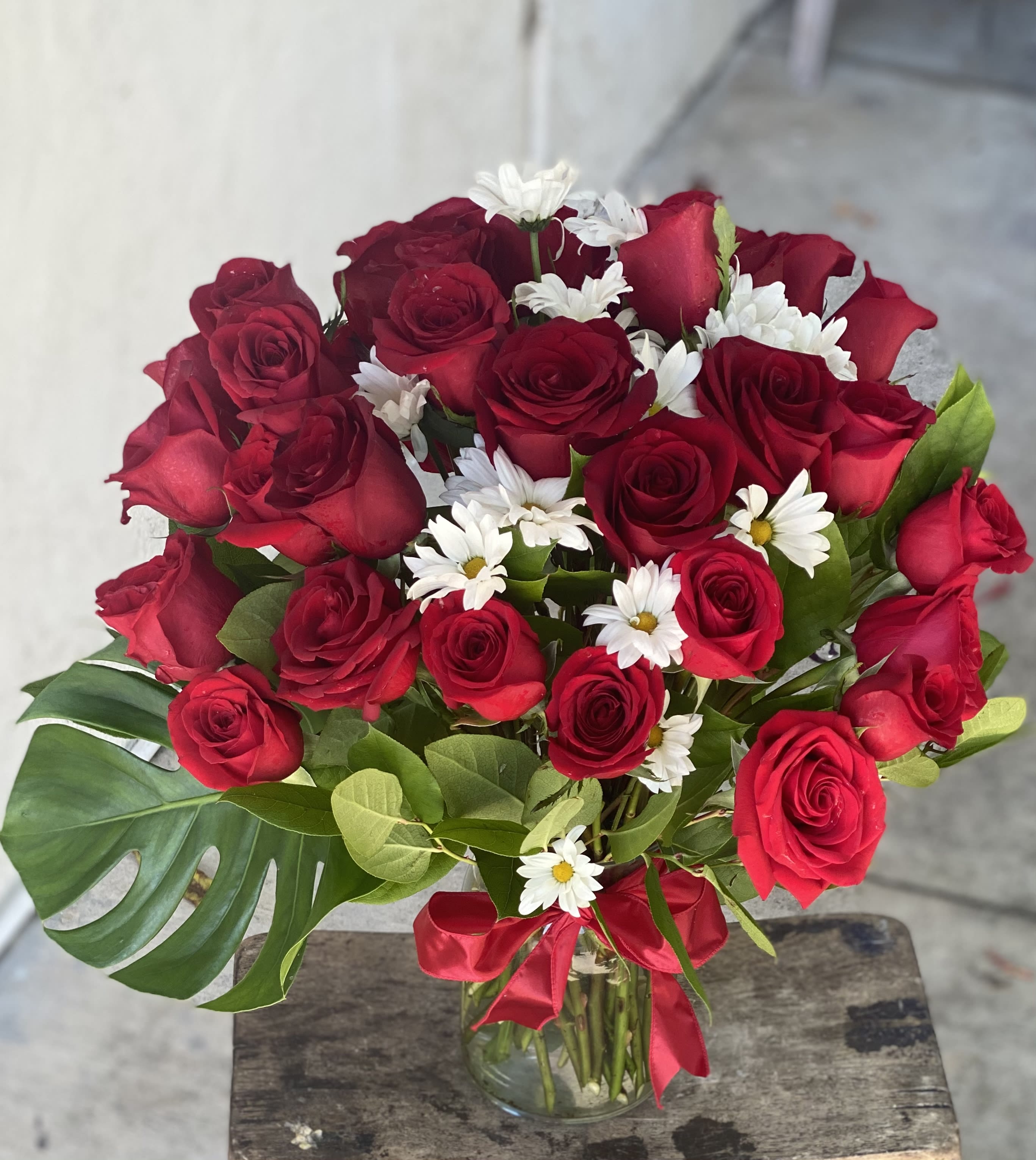 Bouquet of red roses and white daisies in a glass vase