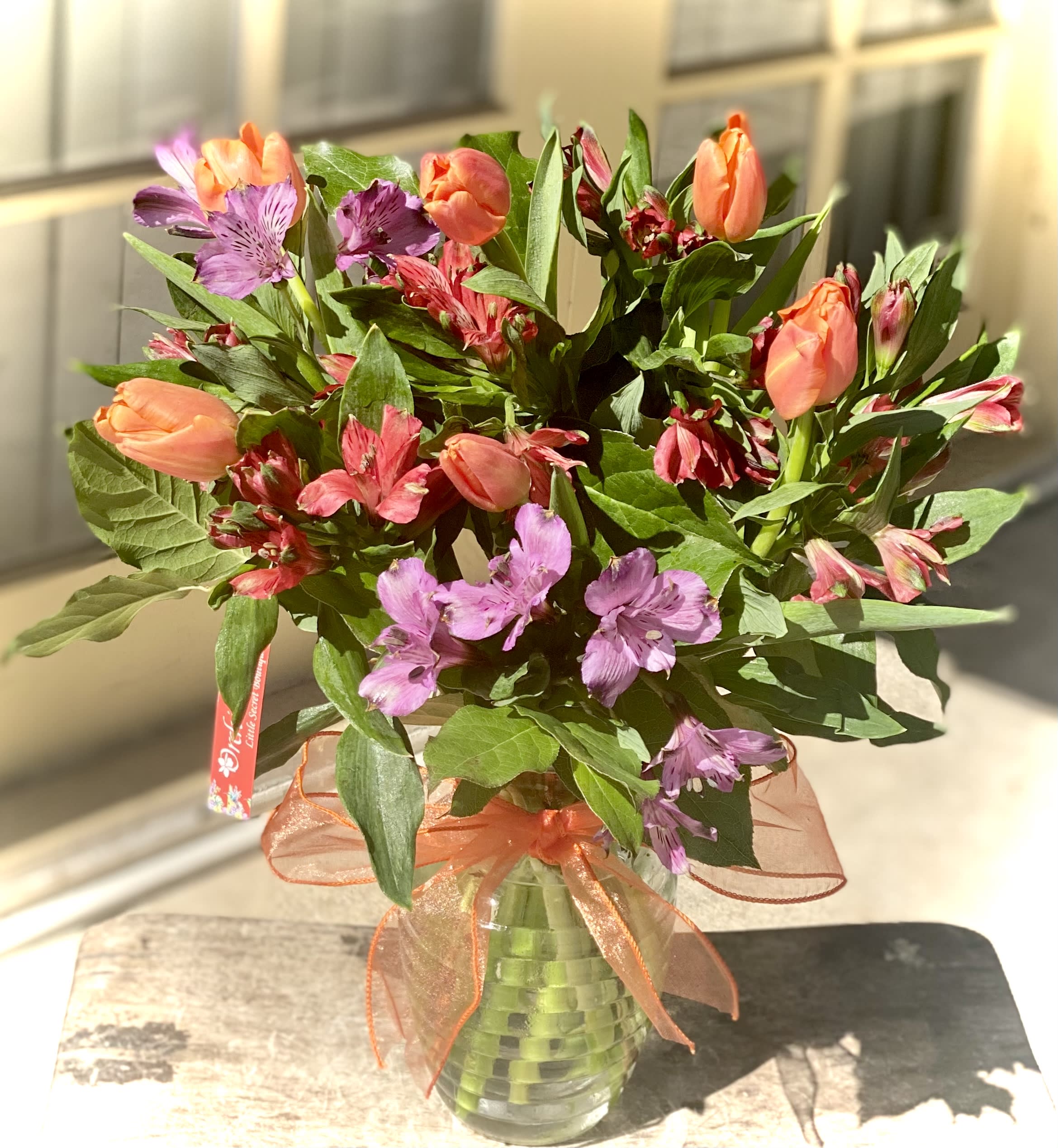 Bouquet of orange tulips and purple alstroemeria in a glass vase