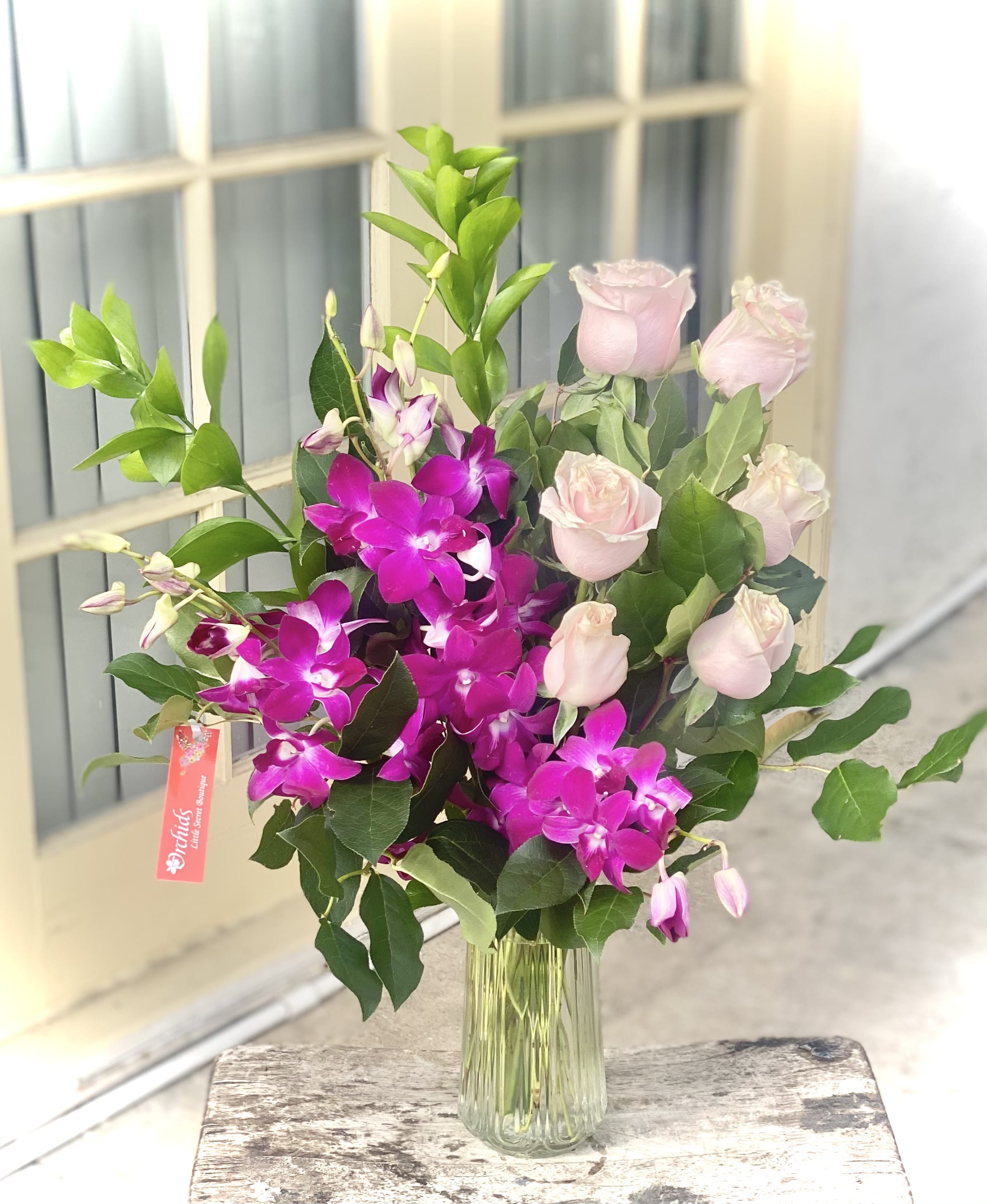 Pink roses and purple orchids in a clear glass vase