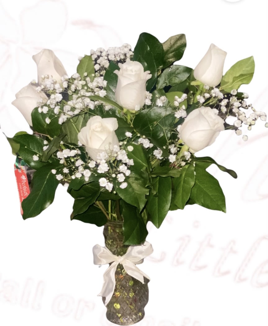 White roses and baby's breath in a glass vase with a ribbon
