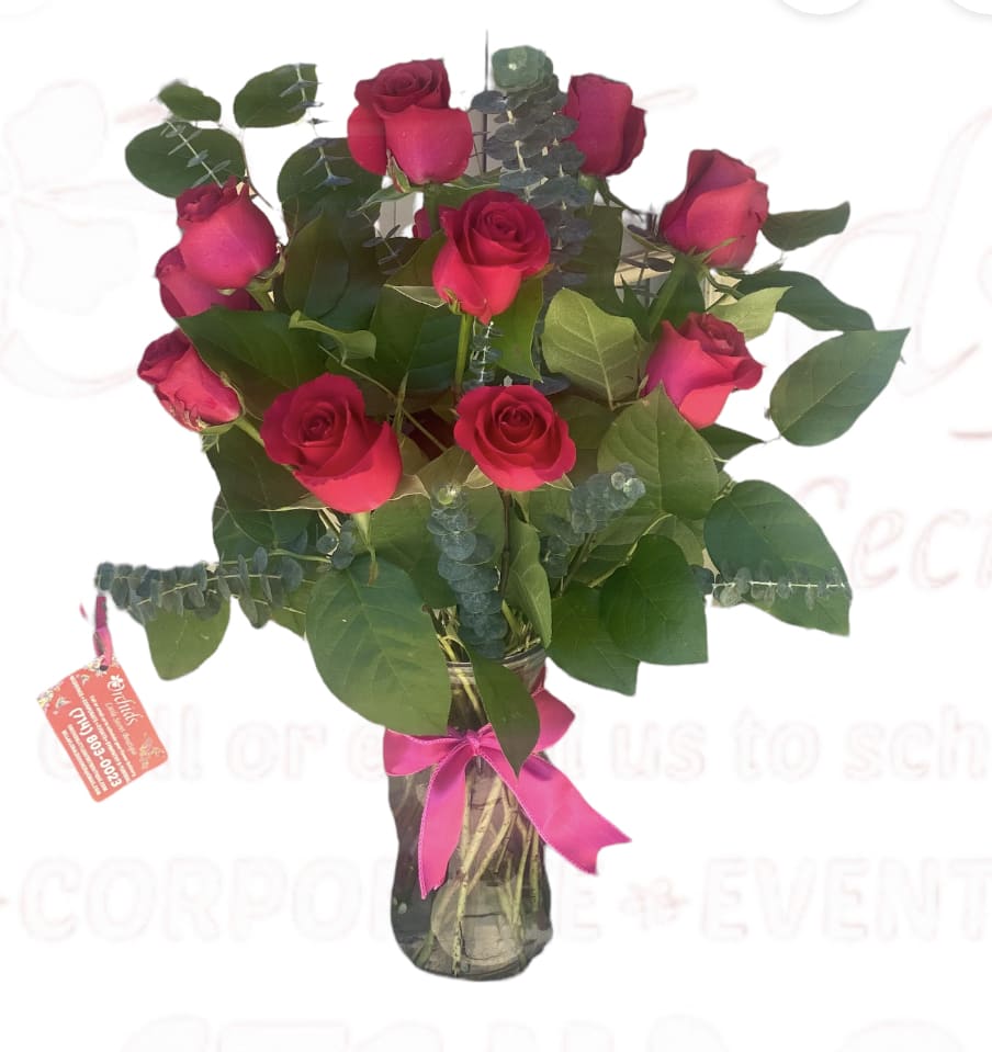Bouquet of red roses in a glass vase with a pink ribbon