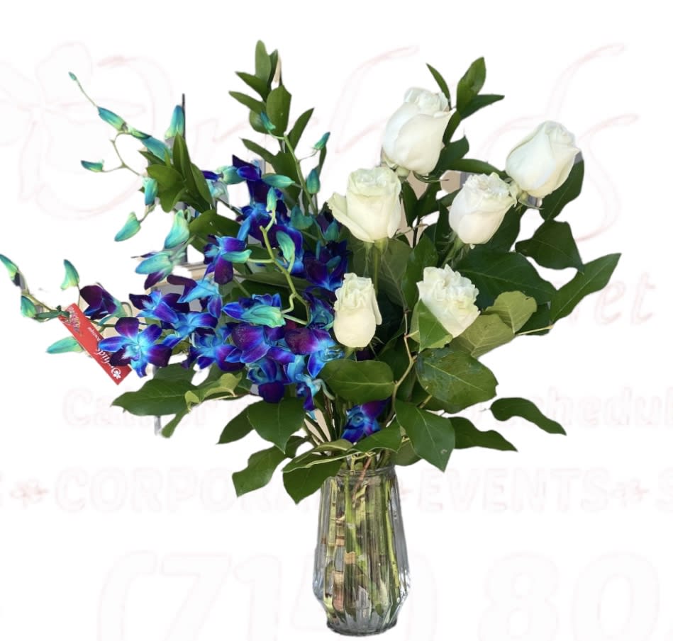 White roses and blue orchids in a clear glass vase