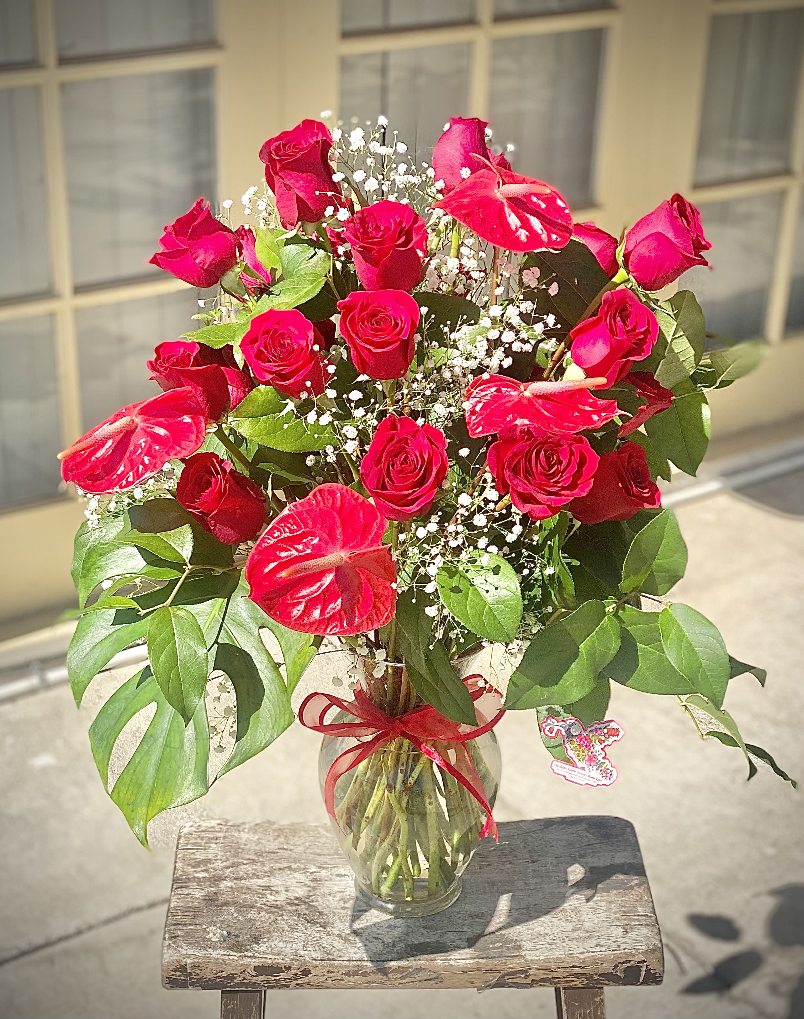 Red roses and anthuriums in a glass vase with baby's breath